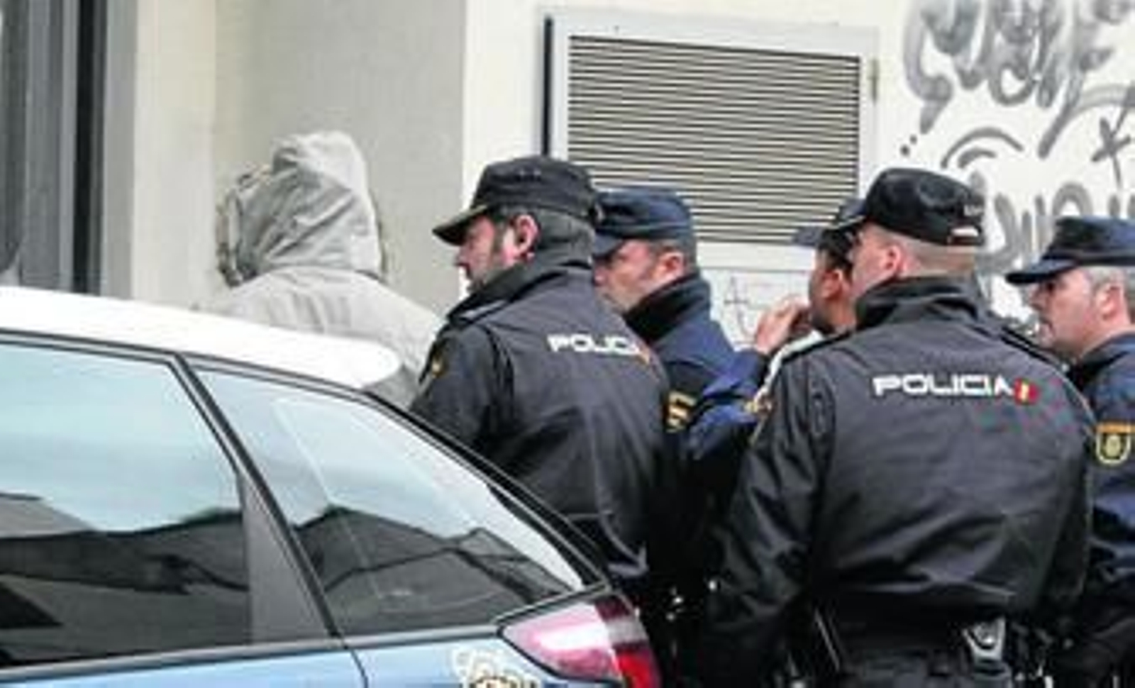 Uno de los detenidos (con capucha), es conducido por la Policía a la tercera planta del inmueble en el que fue retenida la joven.