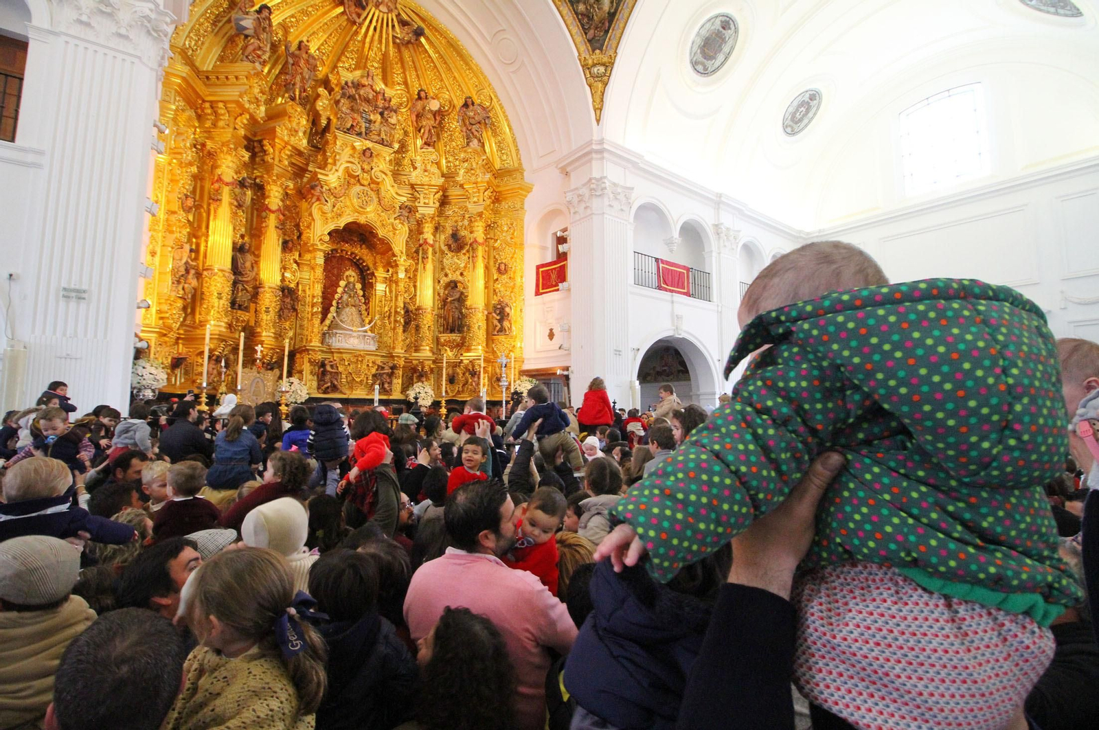 Miles de niños pasan por el manto de la Virgen del Rocío en la festividad de la Candelaria.