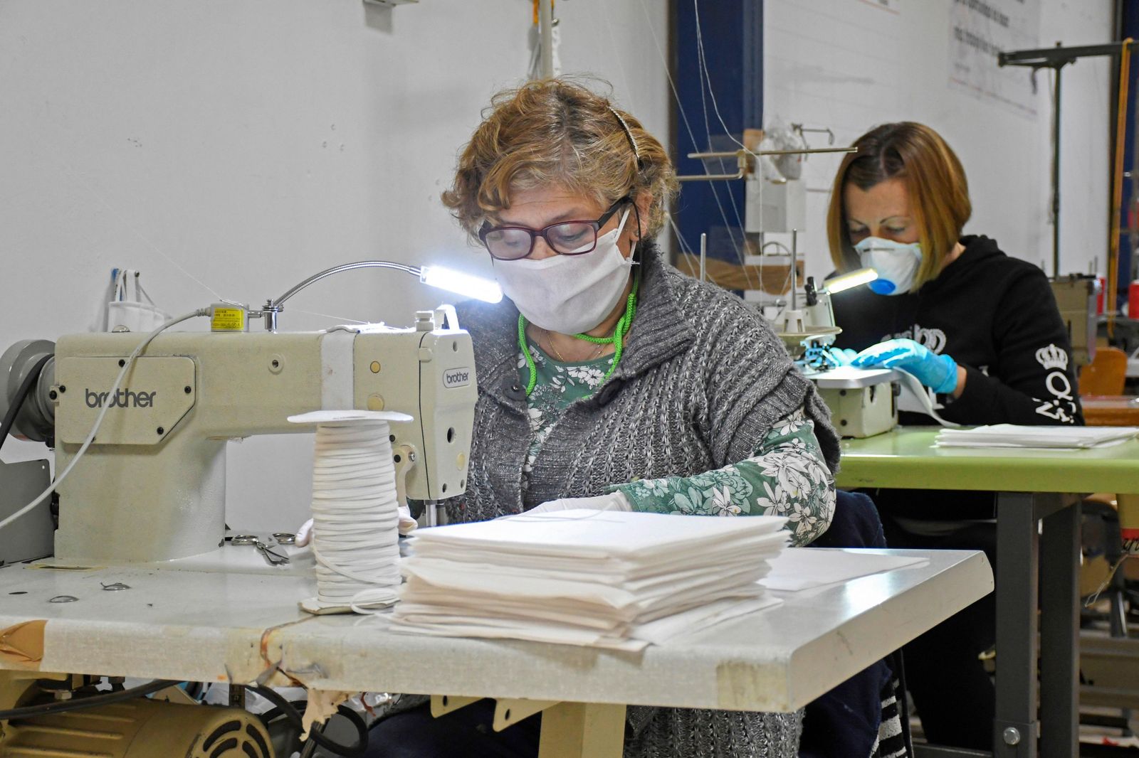 Dos mujeres elaborando mascarillas solidarias en un taller de costura.