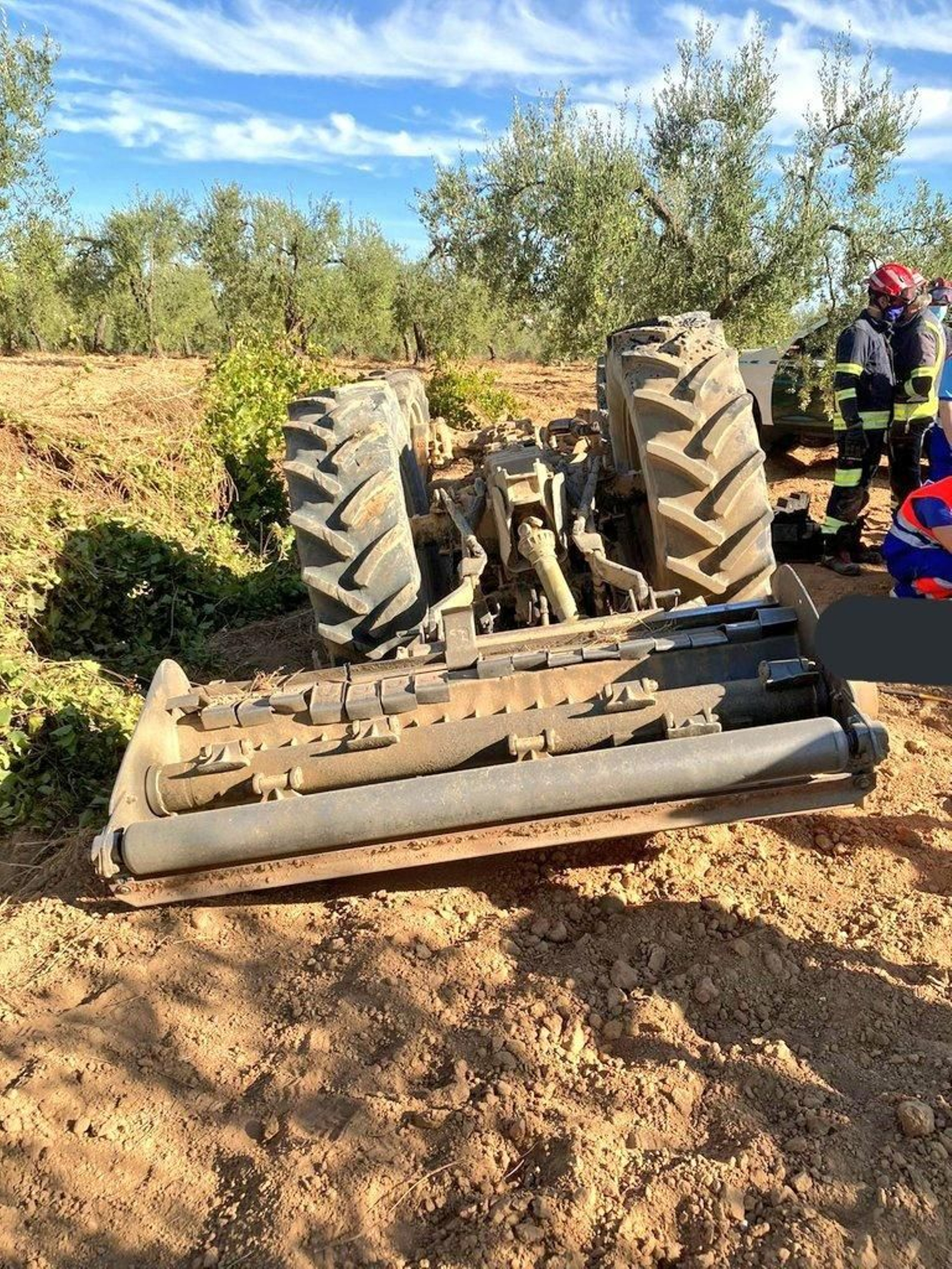 Los Bomberos del Aljarafe, junto al tractor volcado.