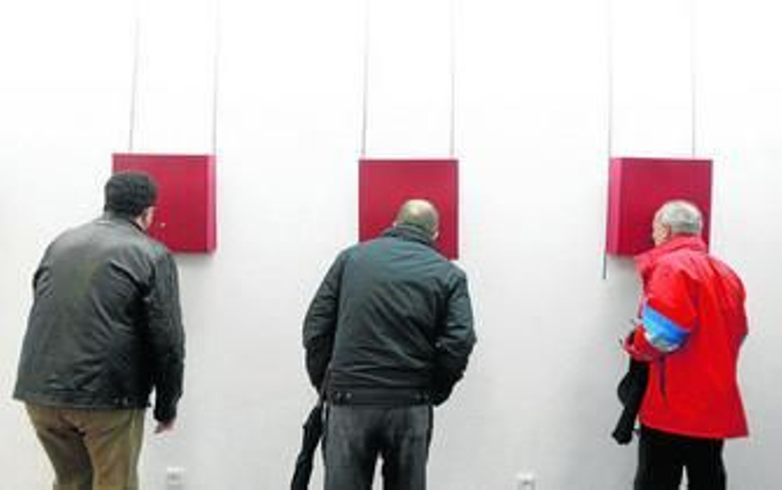 Tres visitantes contemplan obras en la colectiva de Afoco.