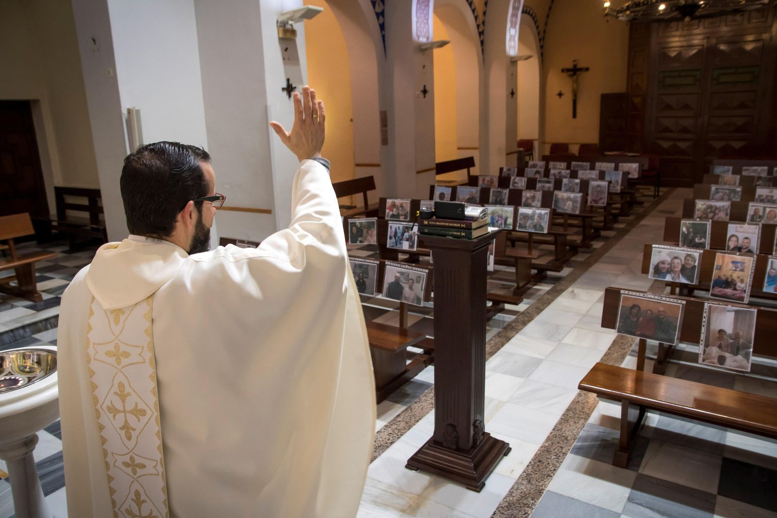 El párroco de Regiones, Antonio Salvador, celebra la misa con los retratos de sus feligreses.