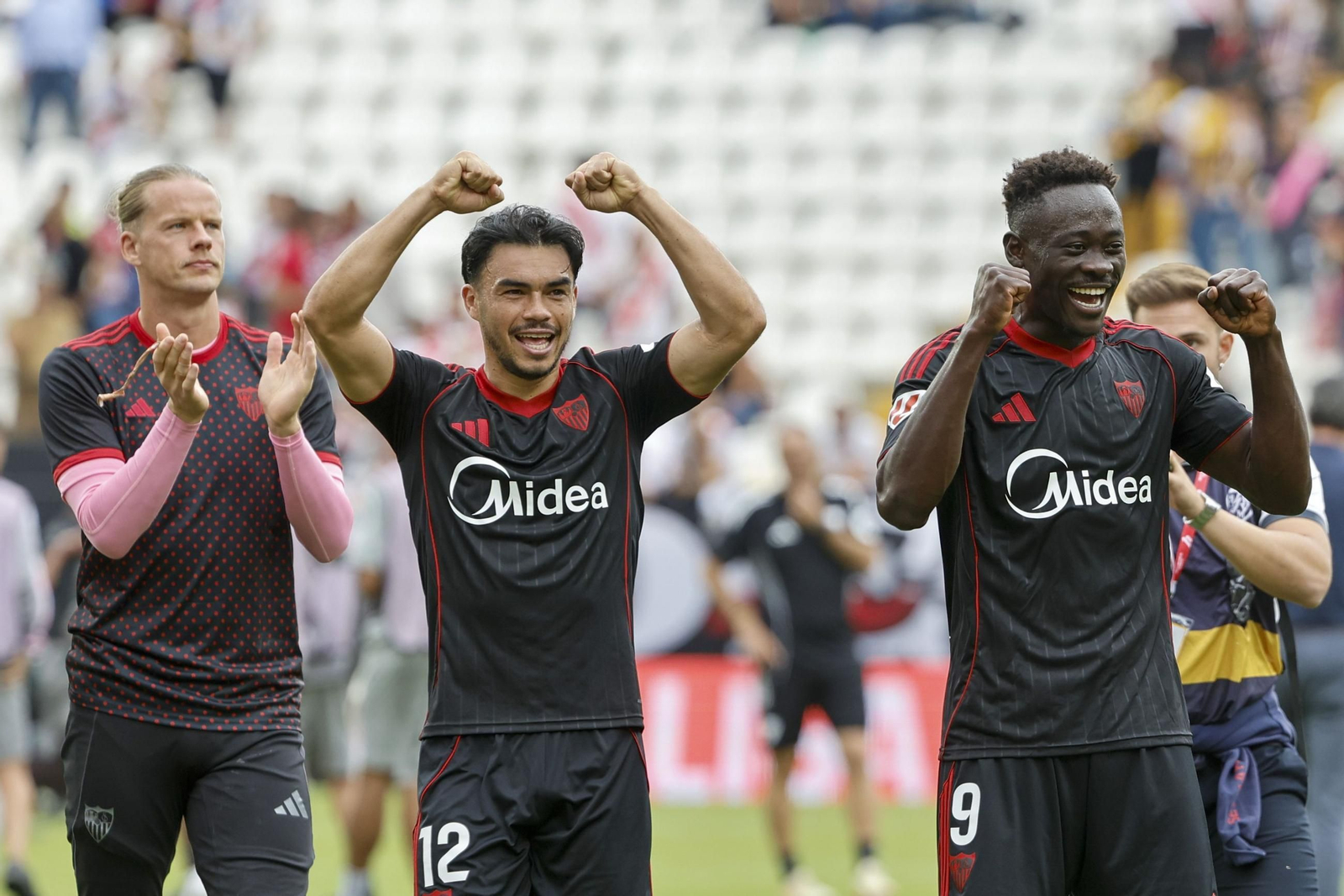 Suazo y Akor Adams, dos de los principales protagonistas del triunfo, festejan con Nyland por detrás la victoria con todos los sevillistas.