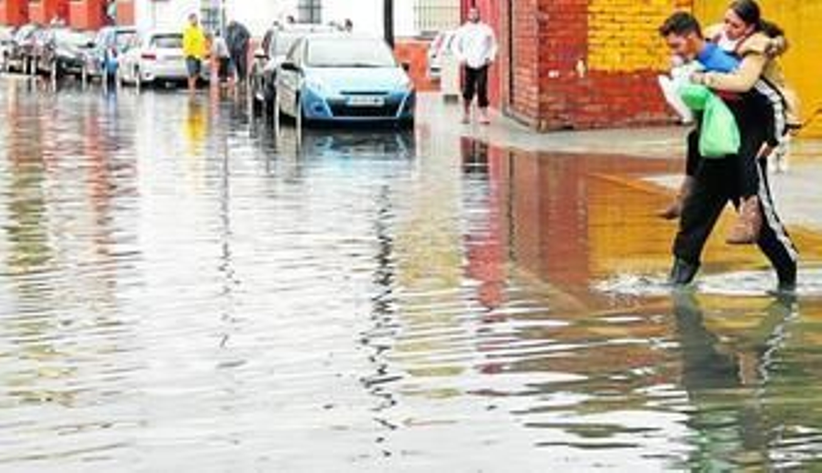 Un hombre lleva a su espalda a una joven durante las inundaciones de noviembre en La Línea.
