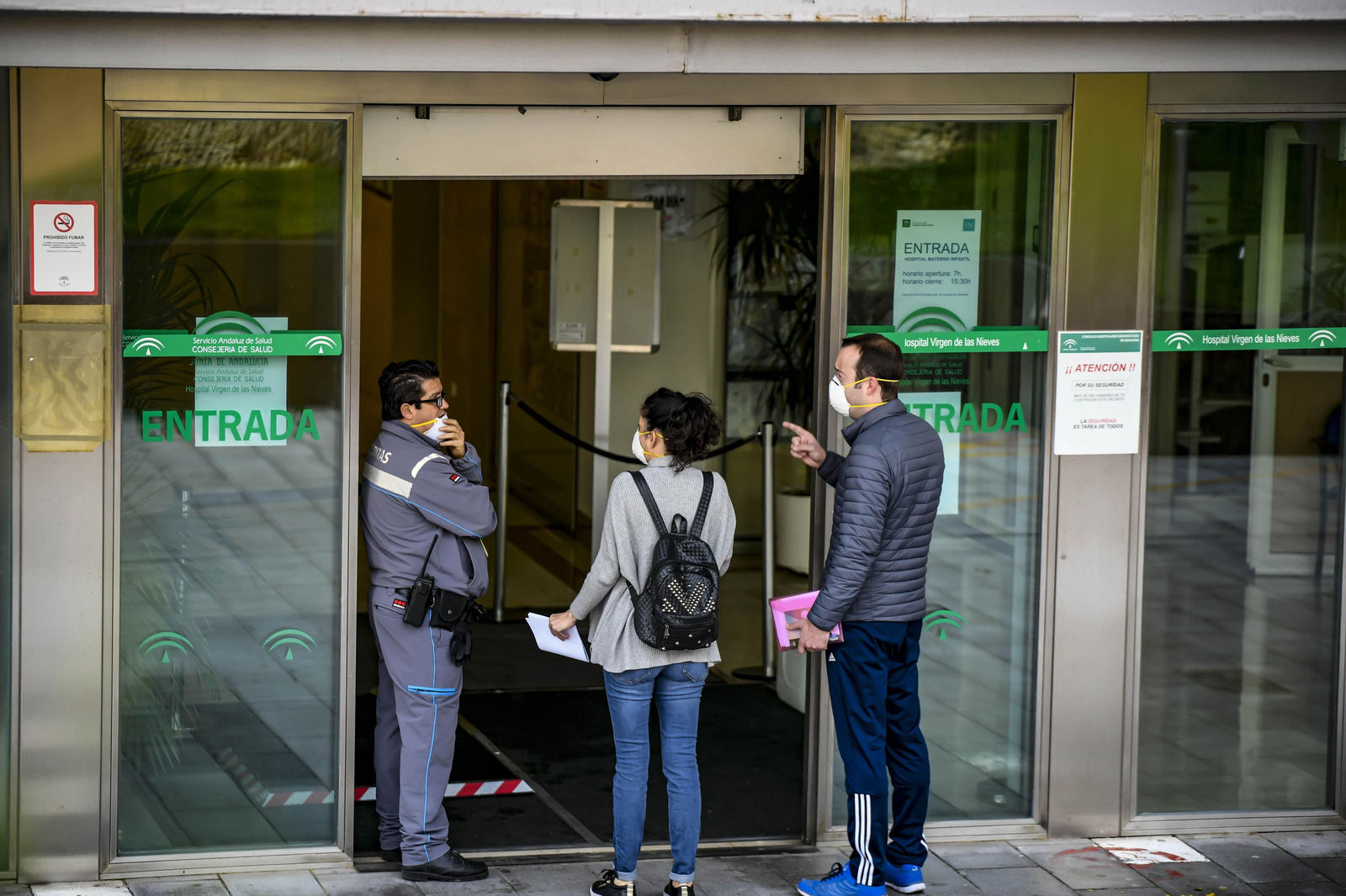Una pareja pregunta a un guardia de seguridad a la puerta de un hospital granadino