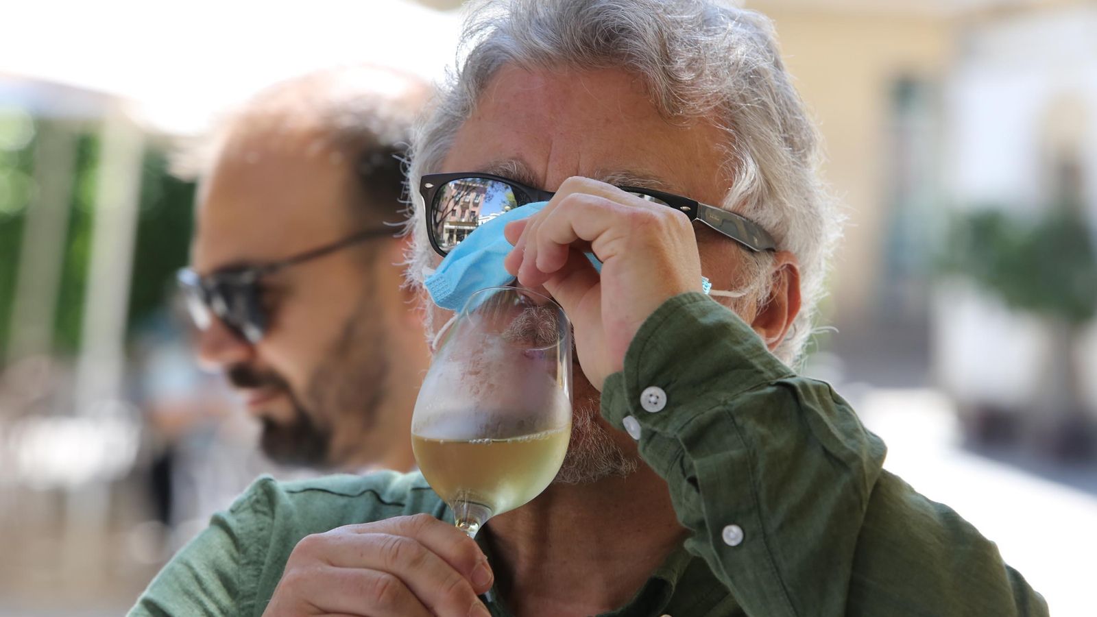 Un consumidor de jerez con mascarilla y copa en mano.