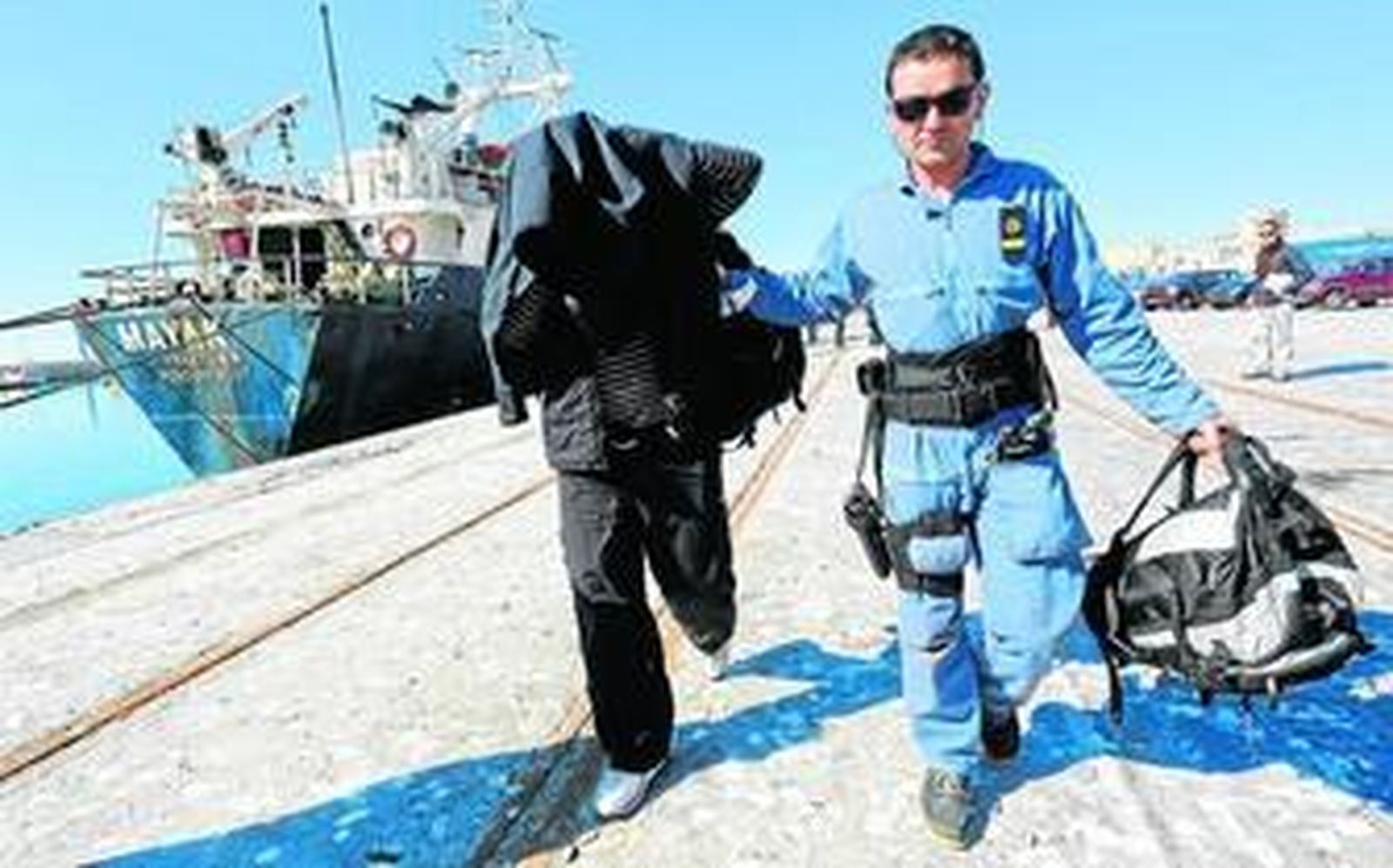 Un agente con uno de los tripulantes del 'Mayak' detenido, ayer en el puerto de Málaga.