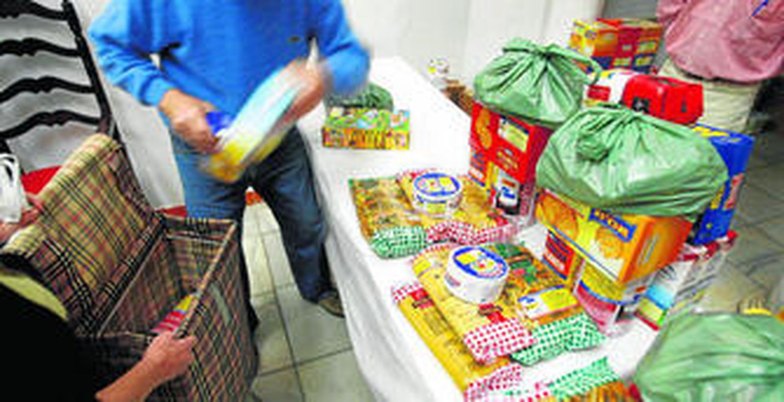 Un voluntario de Cáritas entrega un lote de alimentos a una familia en una imagen de archivo.