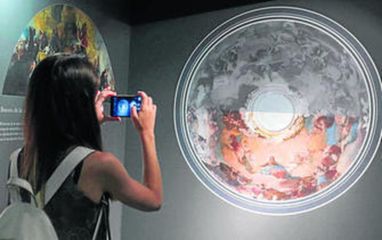 Una joven fotografía una de las láminas que se muestran en la exposición.