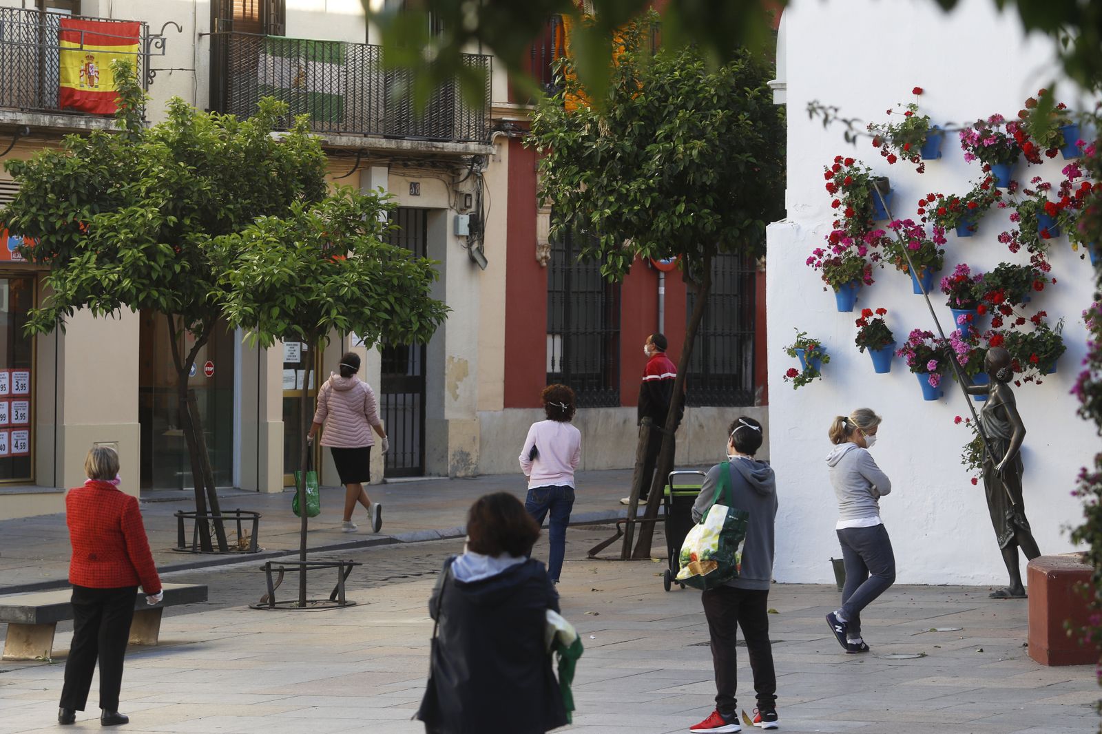 Varias personas hacen cola para entrar a un supermercado.