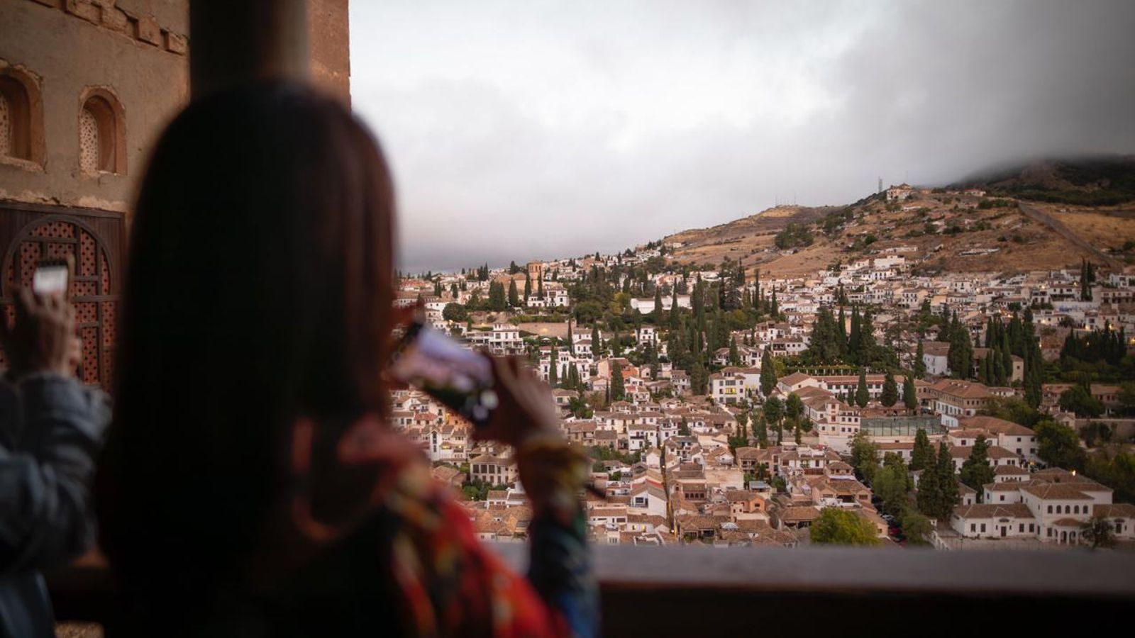 Una mujer fotografía el Albaicín desde la Alhambra