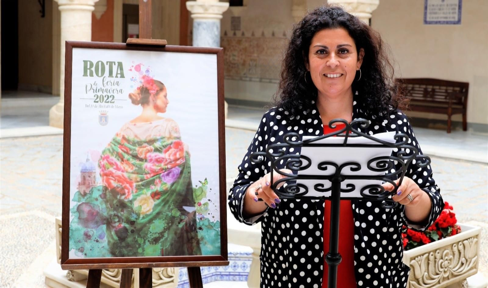 La concejala de Fiestas, Laura Almisas, junto al cartel anunciador de la Feria de Primavera de Rota.