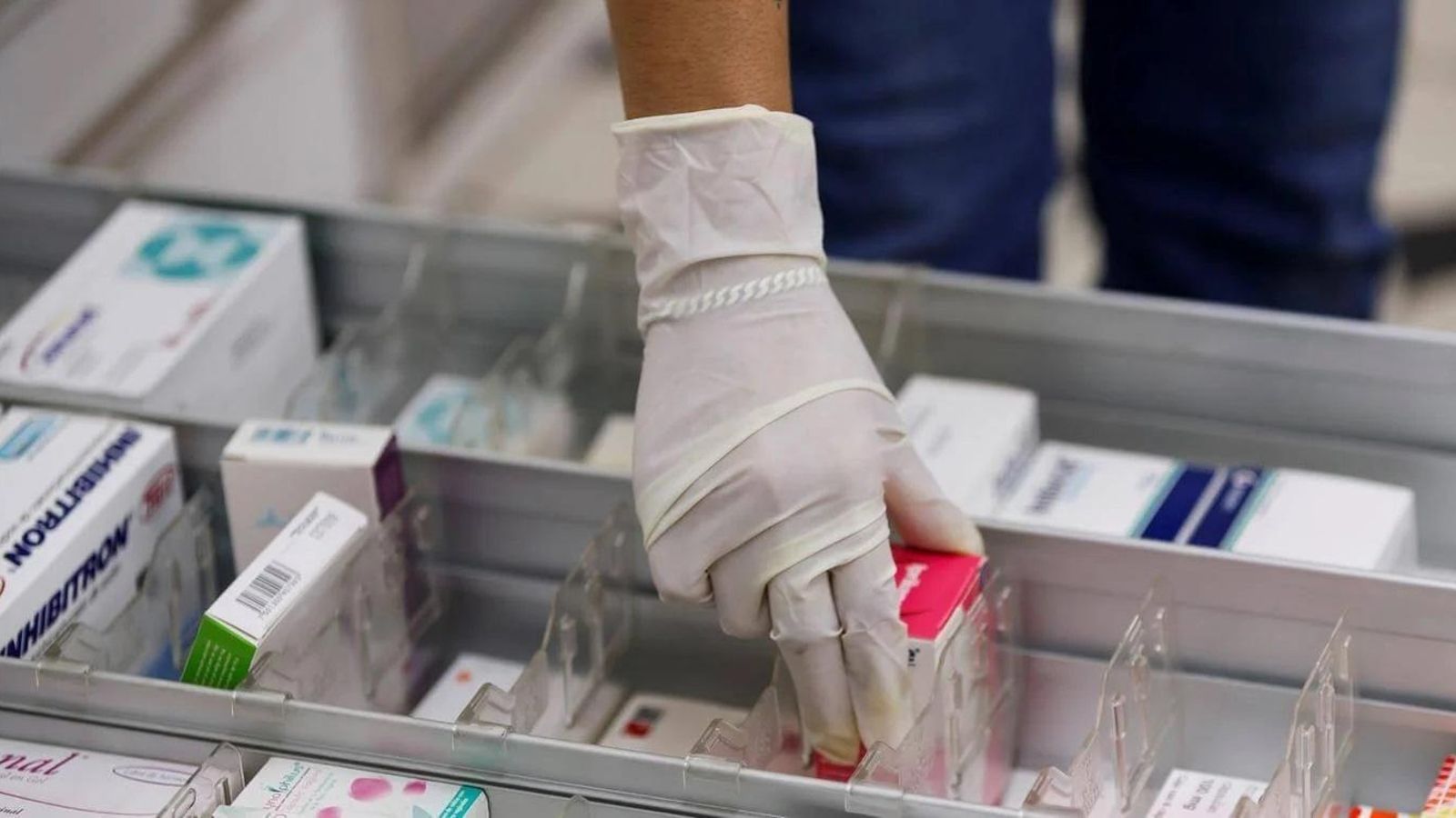 Una farmacéutica coge un medicamento. Una farmacéutica coge un medicamento.