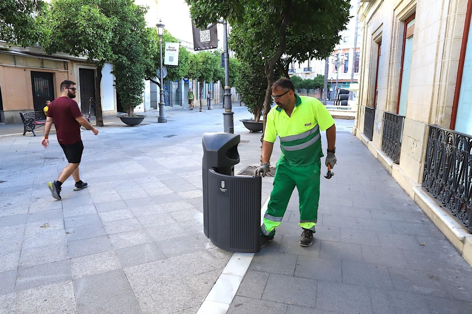 Un operario municipal de la limpieza junto a una de las nuevas papeleras instaladas en la calle Larga.