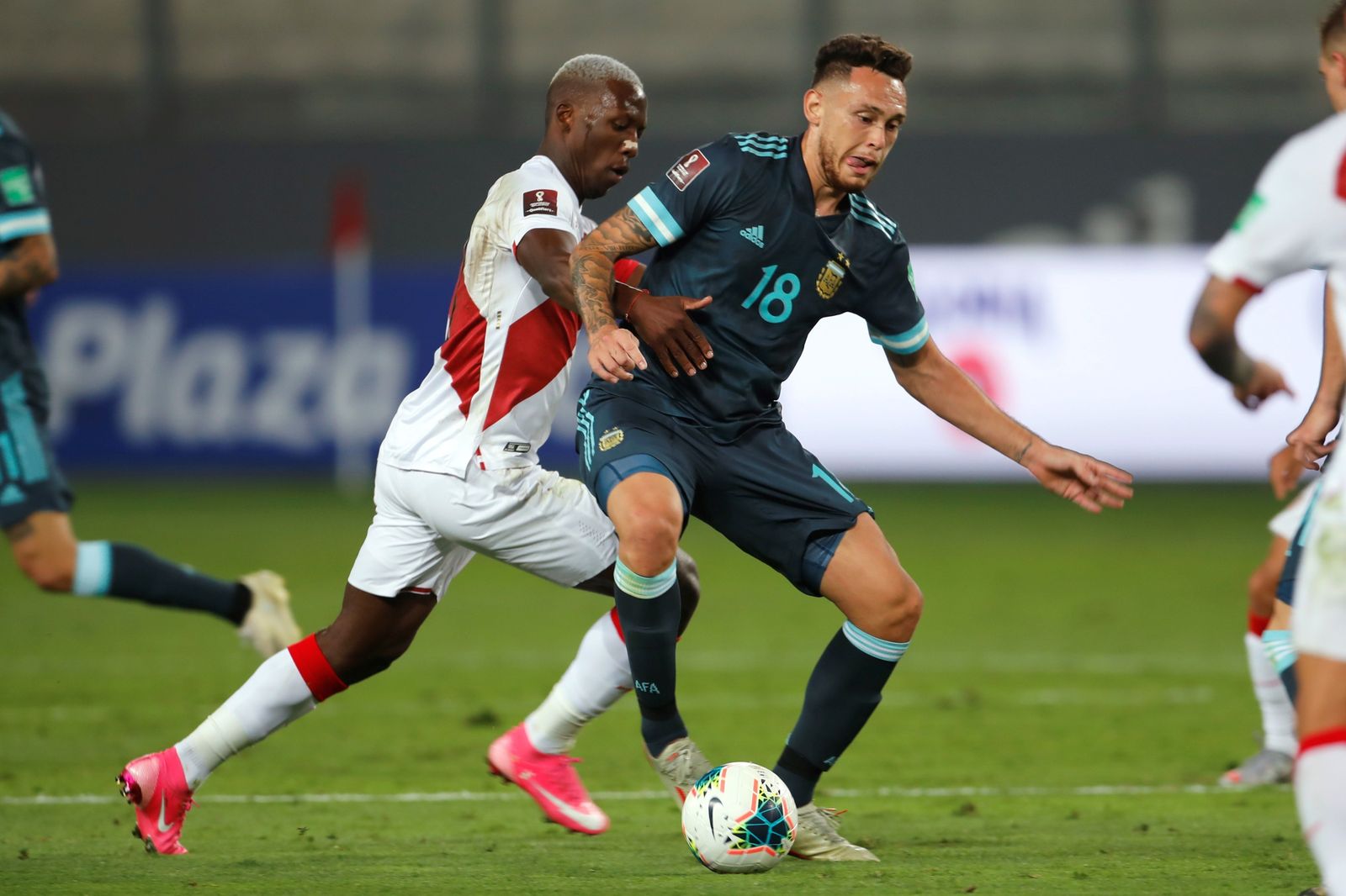 Lucas Ocampos avanza mientras es agarrado por Luis Advíncula en el Perú-Argentina.