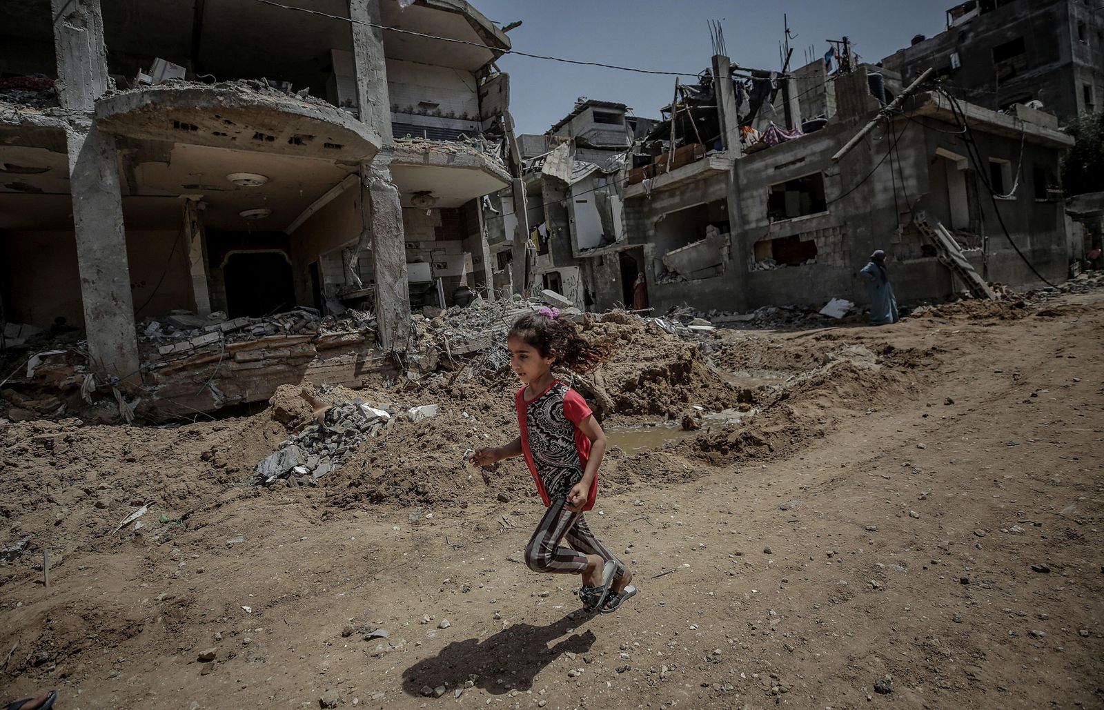 Una niña palestina corre junto a su casa destruida en Gaza.