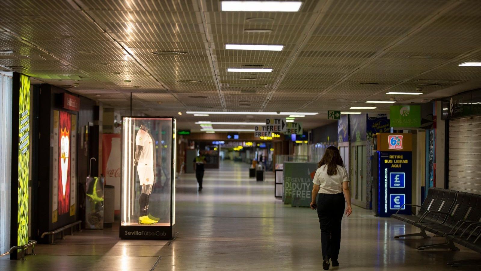 Pasillo sin vida comercial ni de pasajeros de acceso a las salas de embarque en el aeropuerto de Sevilla, esta mañana. A partir del 1 de julio abren algunas zonas de restauración y venta.