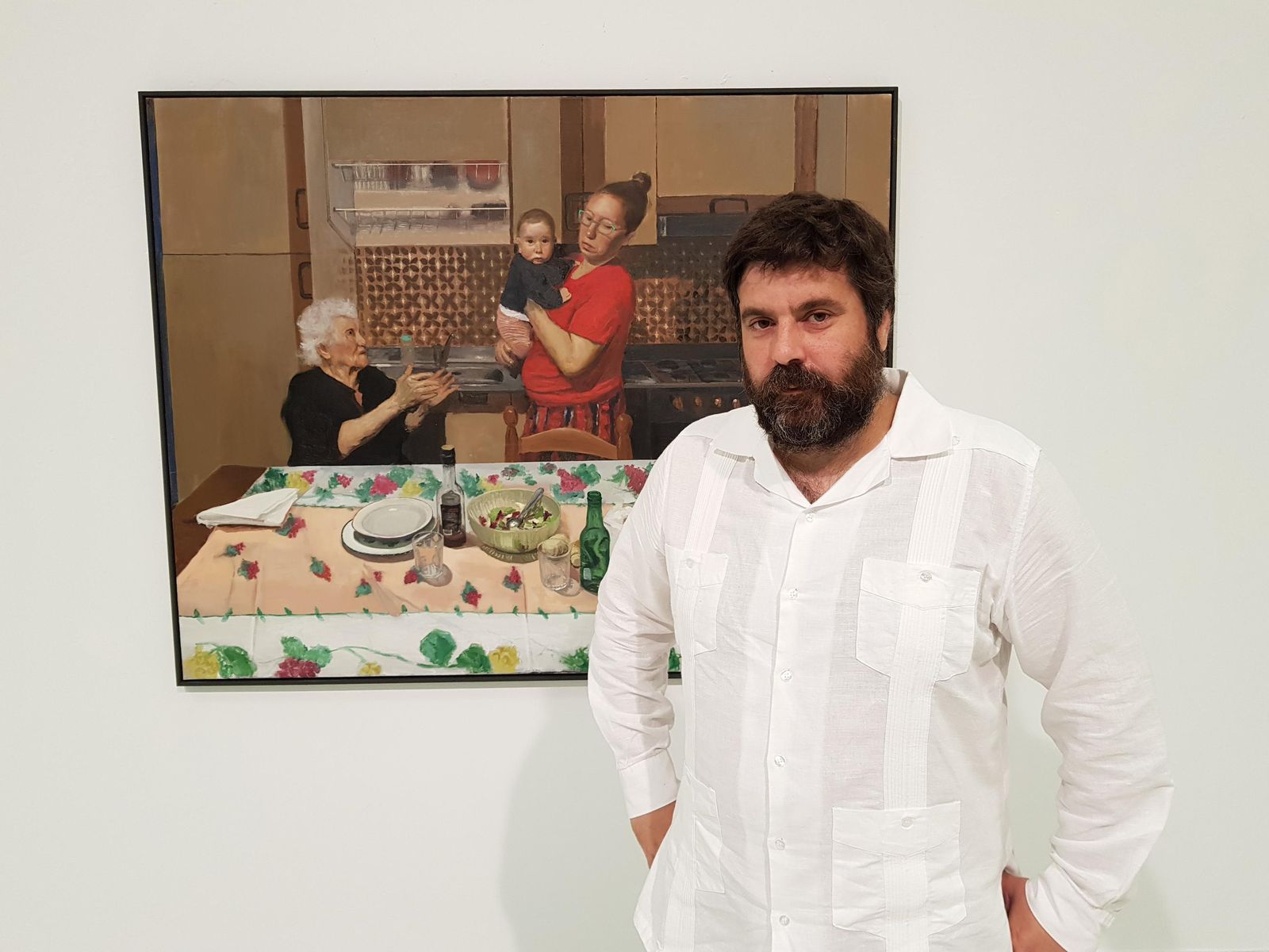 El pintor Pepe Baena posando junto al cuadro 'La cena'.