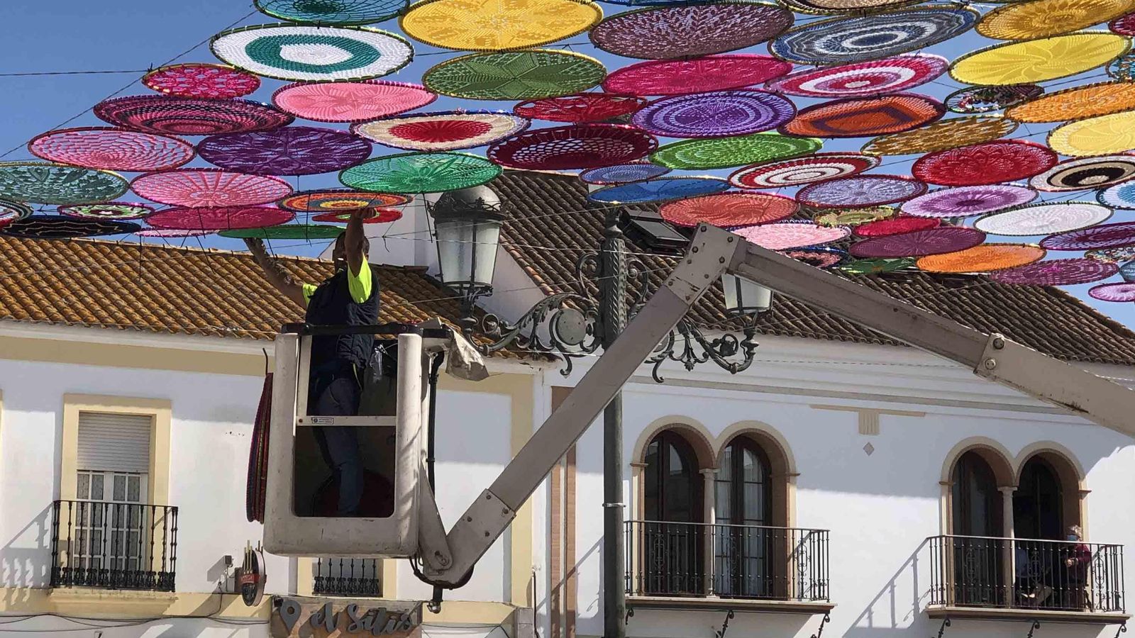Un operario entoldando con aros de croché la plaza redonda de Cartaya