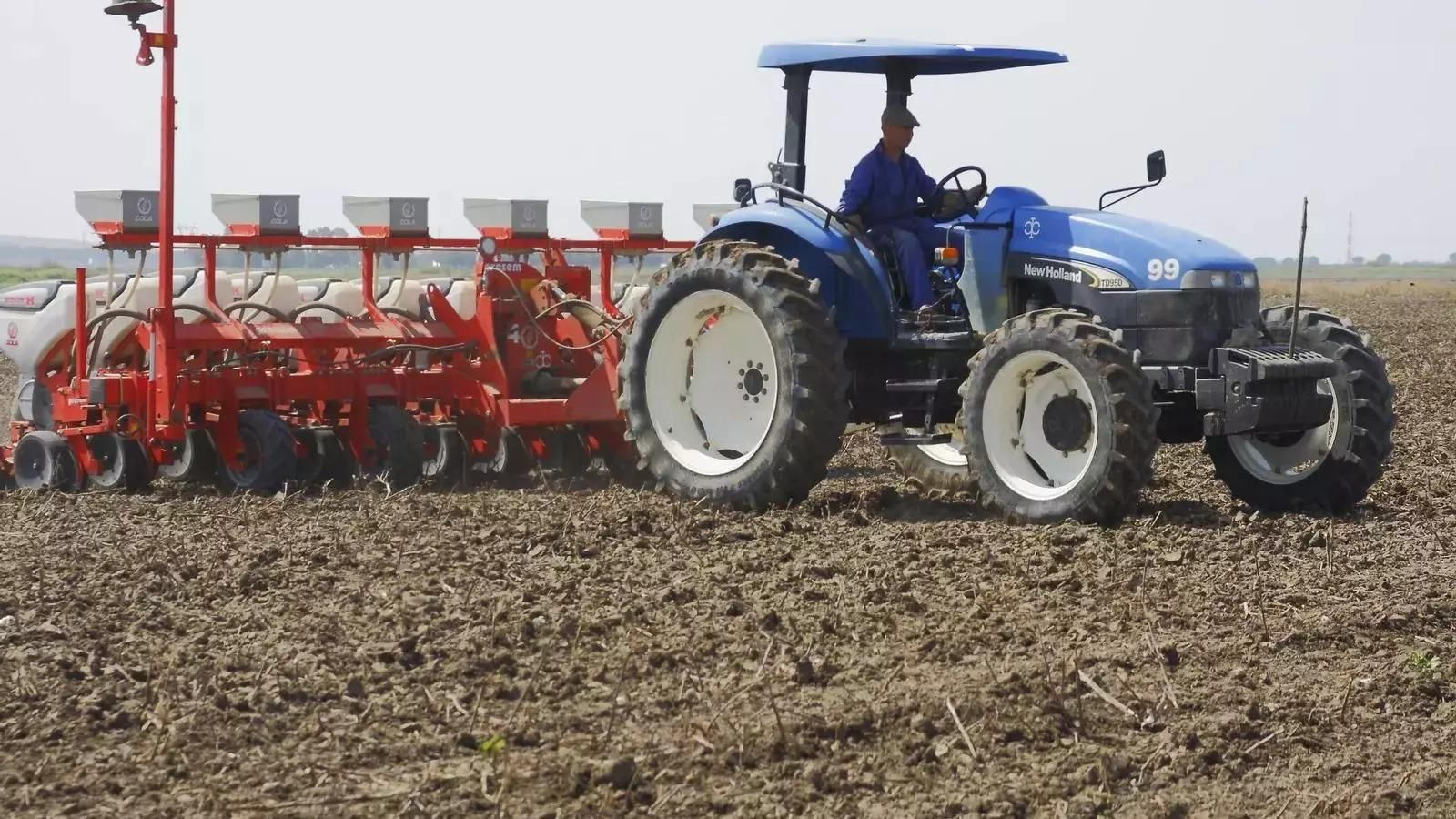 Un agricultor realiza labores agrícolas en una explotación con ayuda de un tractor.