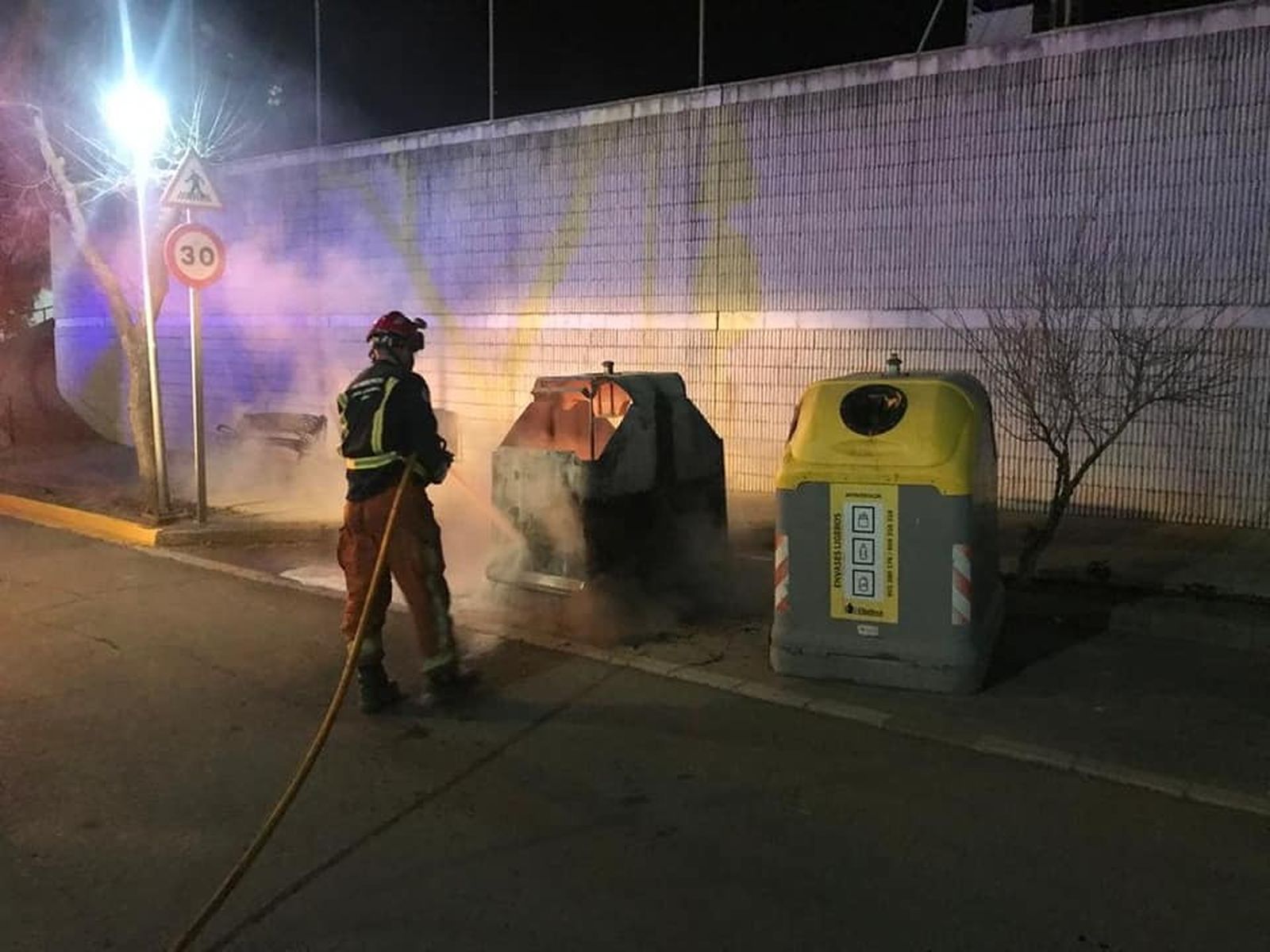 Un bombero extingue las llamas en uno de los contenedores afectados