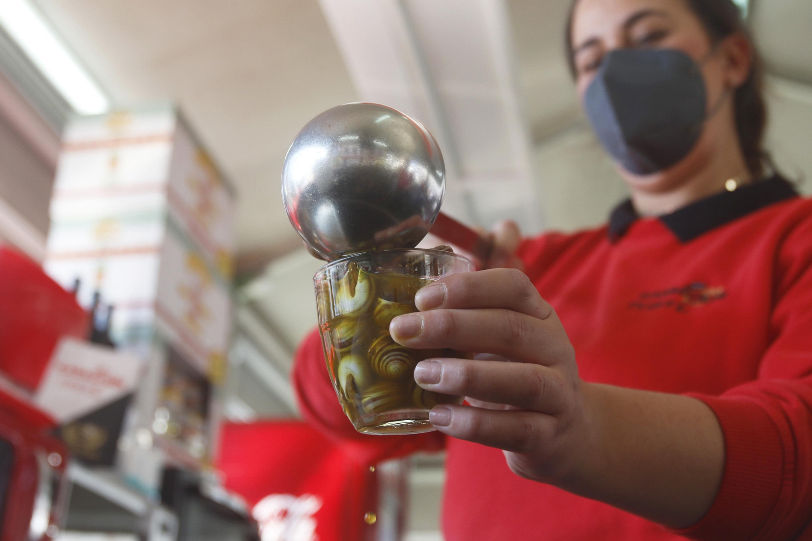 Pepa González sirve un vaso de caracoles en el puesto Peque II.