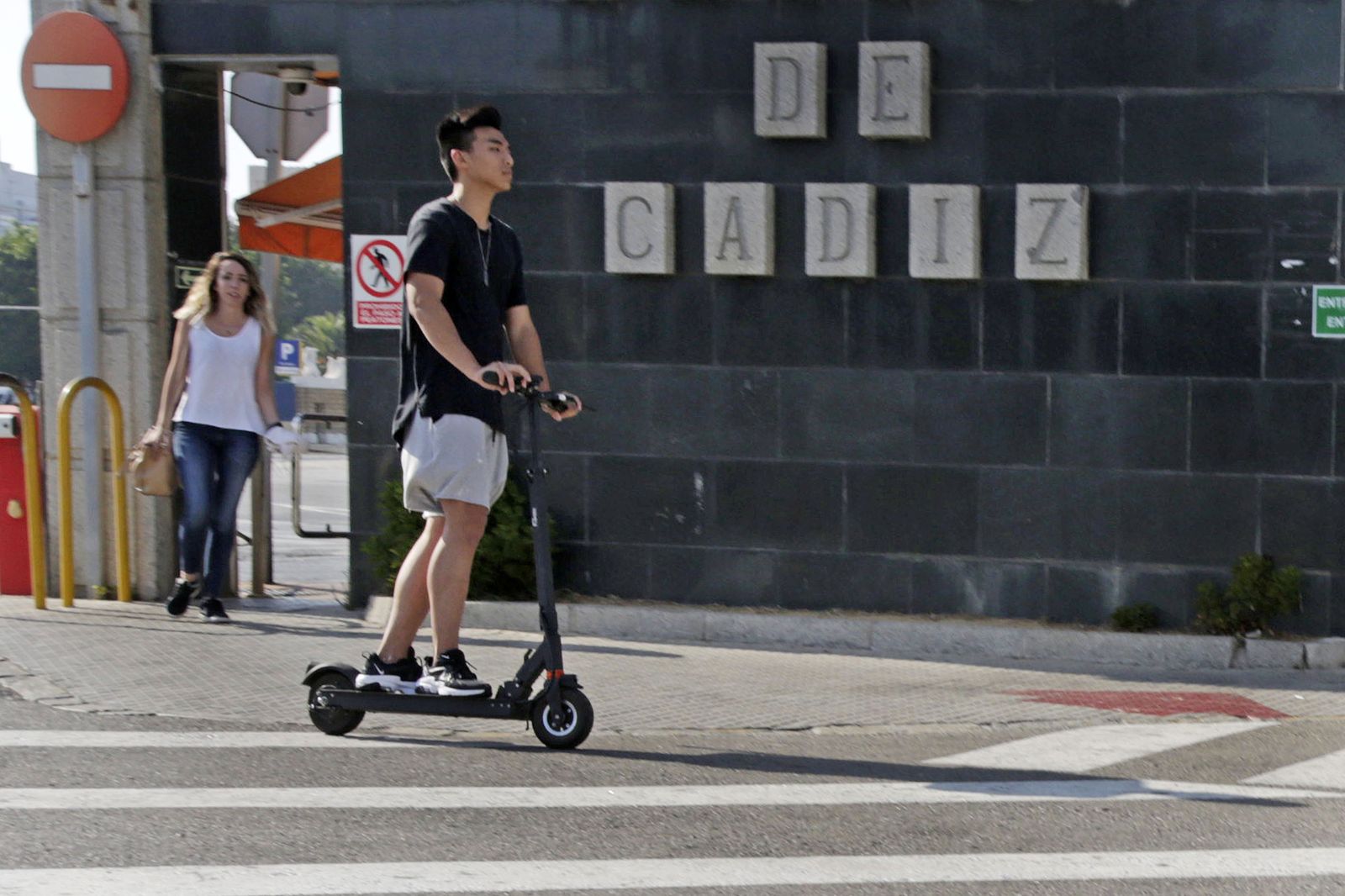 Un joven circula en patinete frente al muelle de Cádiz.