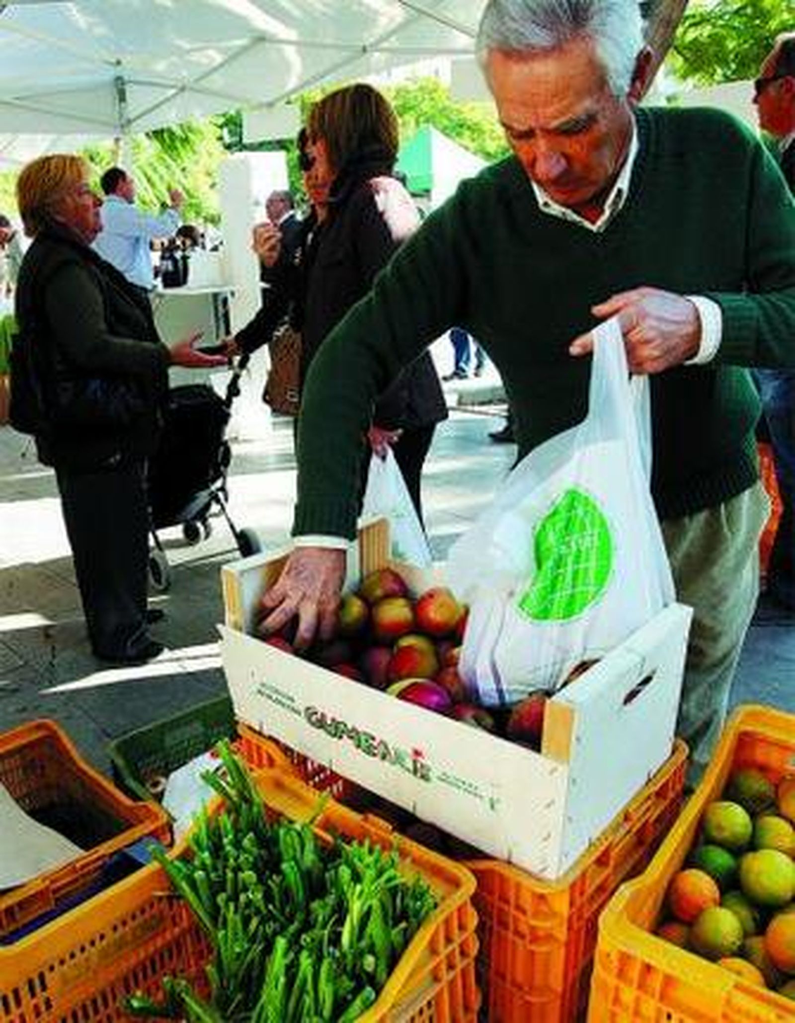 Un hombre coge unas manzanas ecológicas, ayer en la feria.