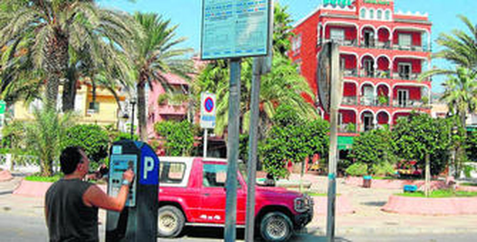 Un ciudadano paga el ticket de aparcamiento debajo de la señal que informa de que ya no es necesario.