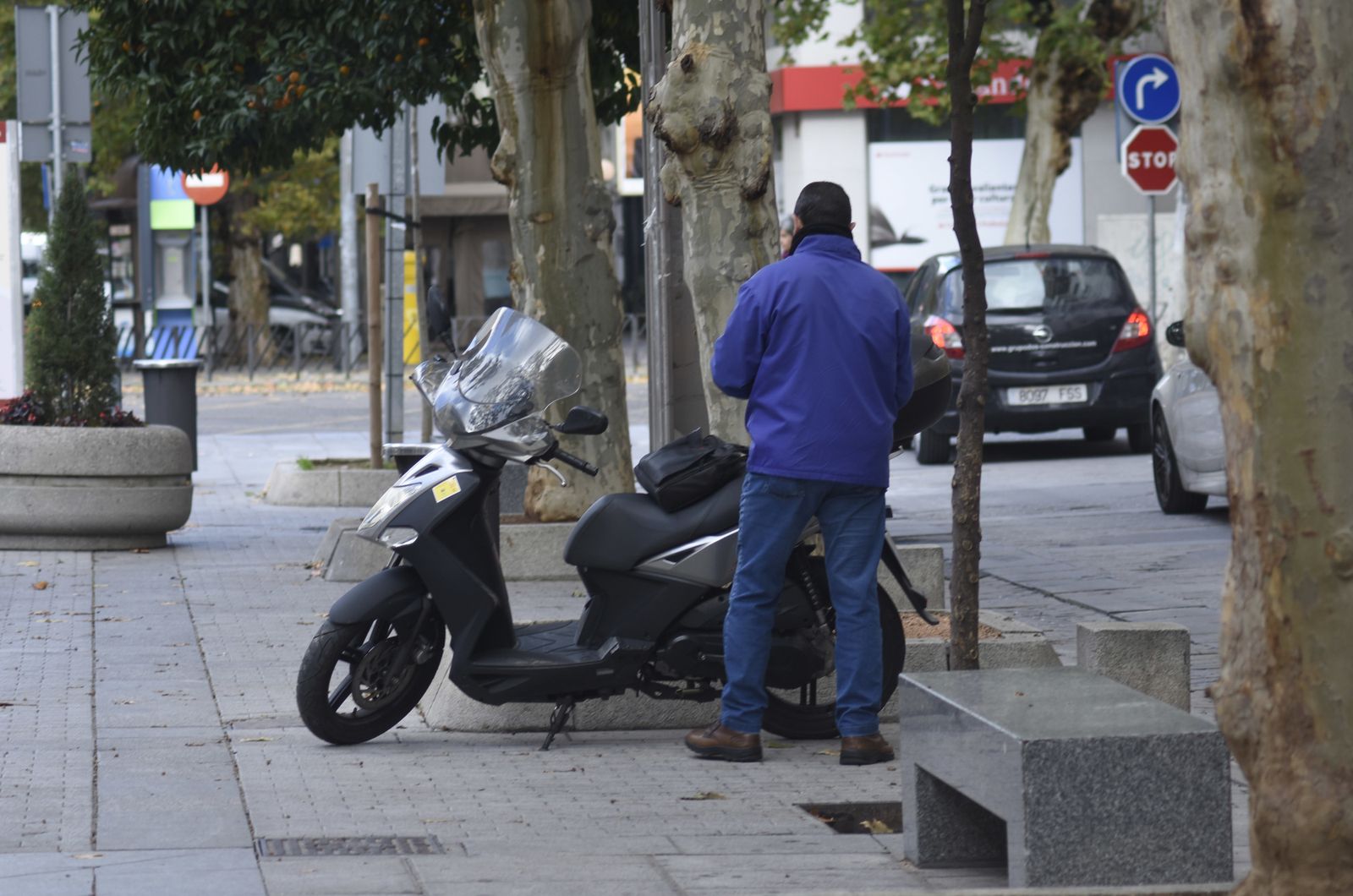 Un hombre espera junto a su moto, en la zona donde la Policía prohíbe aparcar.
