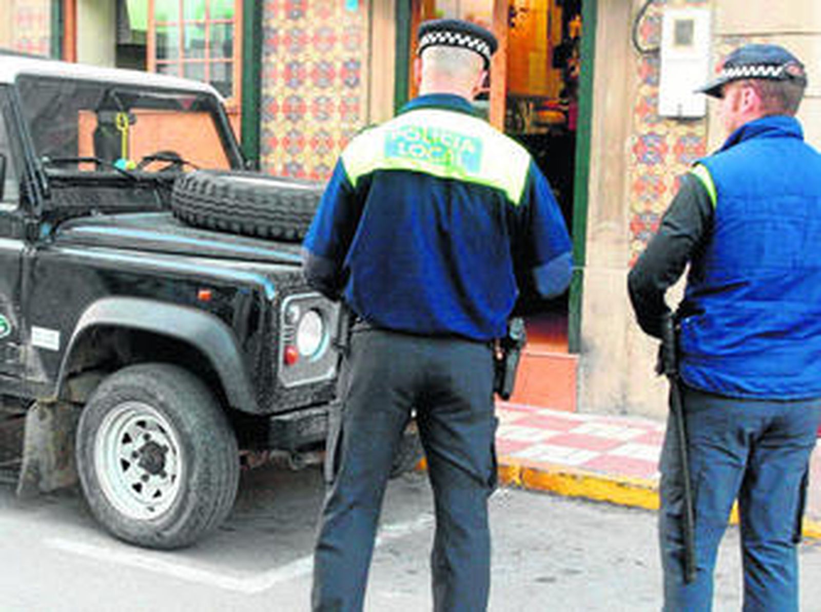 Dos agentes de la Policía Local se disponen a multar a un vehículo aparcado en una zona reservada a minusválidos.