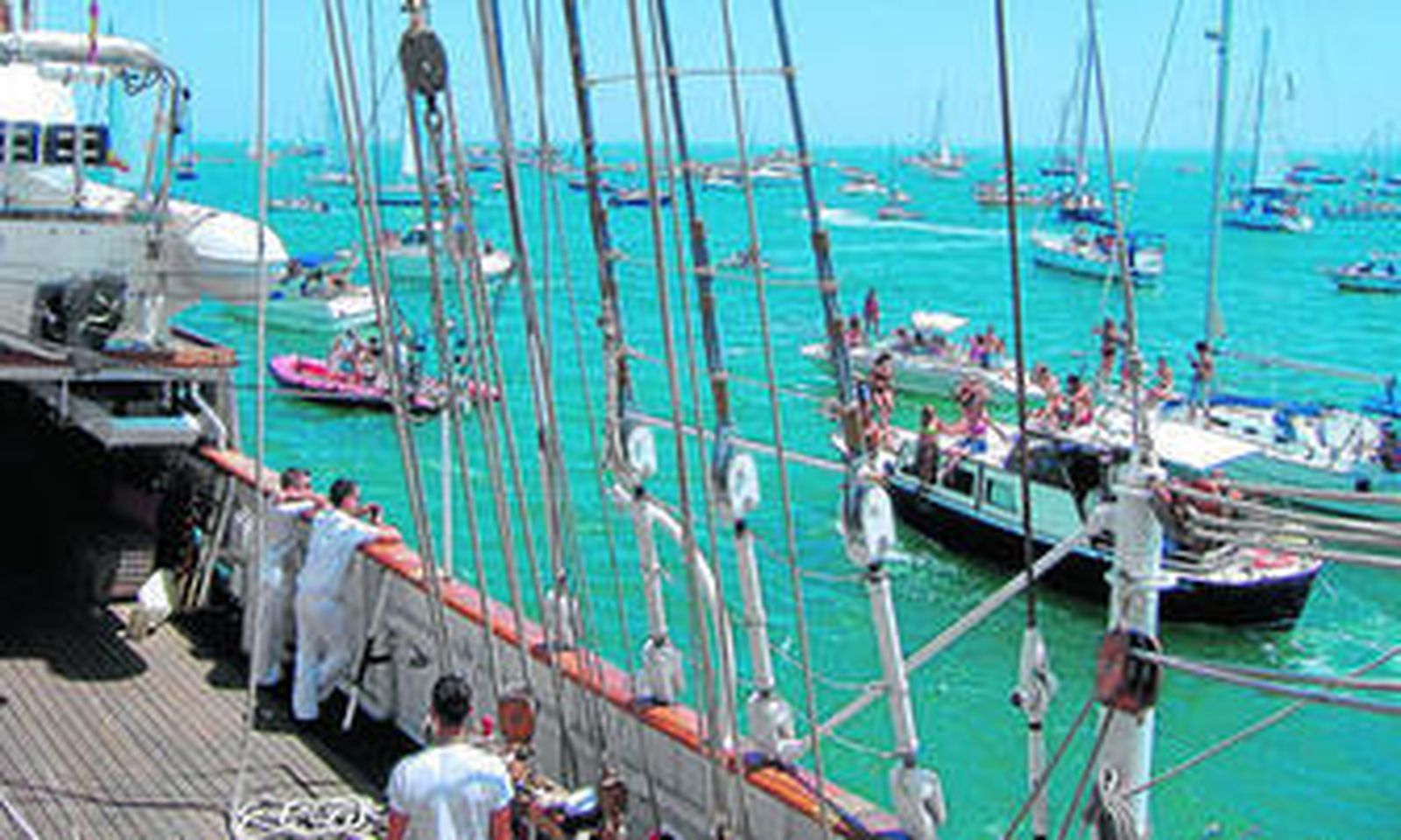 Parte de la tripulación observa las numerosas embarcaciones que acompañan a 'Elcano' en su salida.