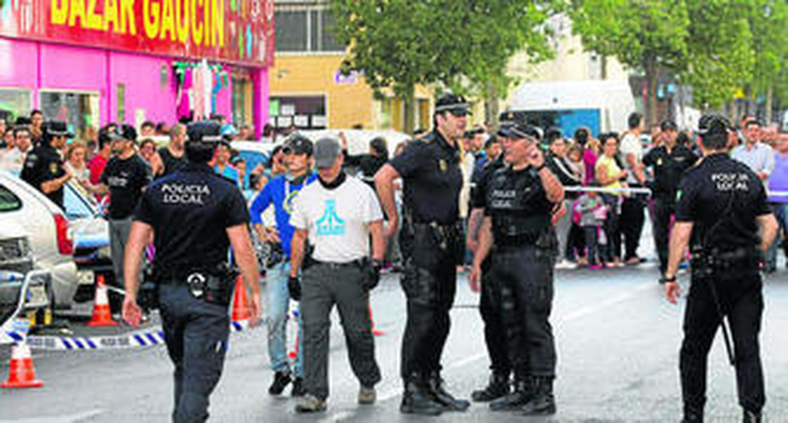 Agentes de policía, ayer en la calle Frigiliana, en Málaga, con los vecinos agolpados tras el cordón. En la foto pequeña, el policía muerto.