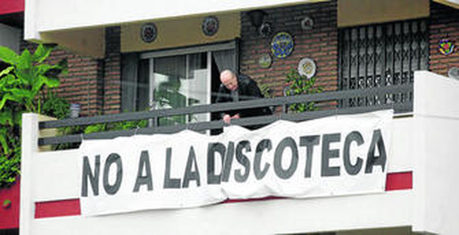 Un vecino cuelga un cartel de protesta por los efectos del centro de ocio.