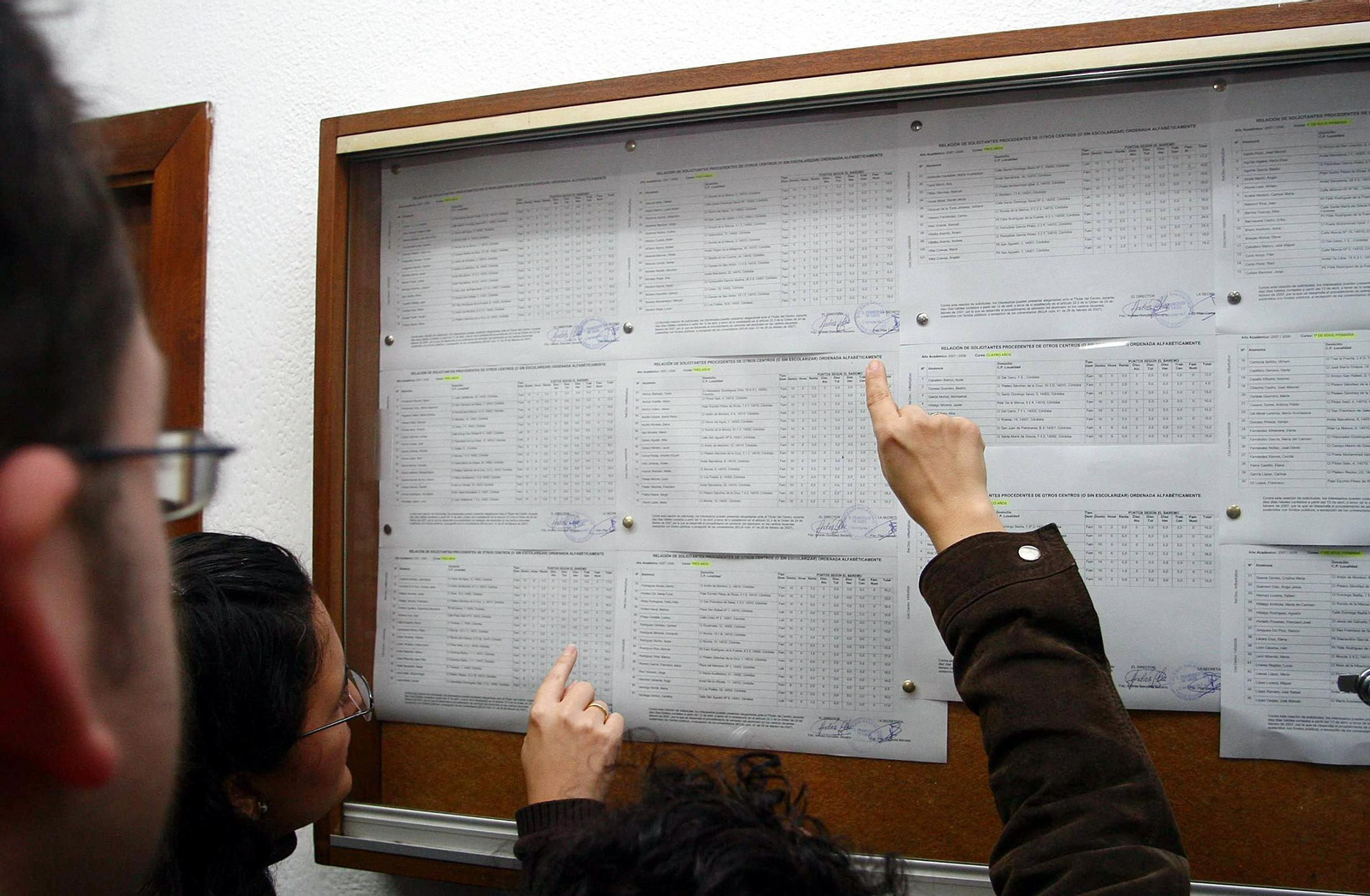 Los padres comprueban el listado de solicitudes en un colegio.