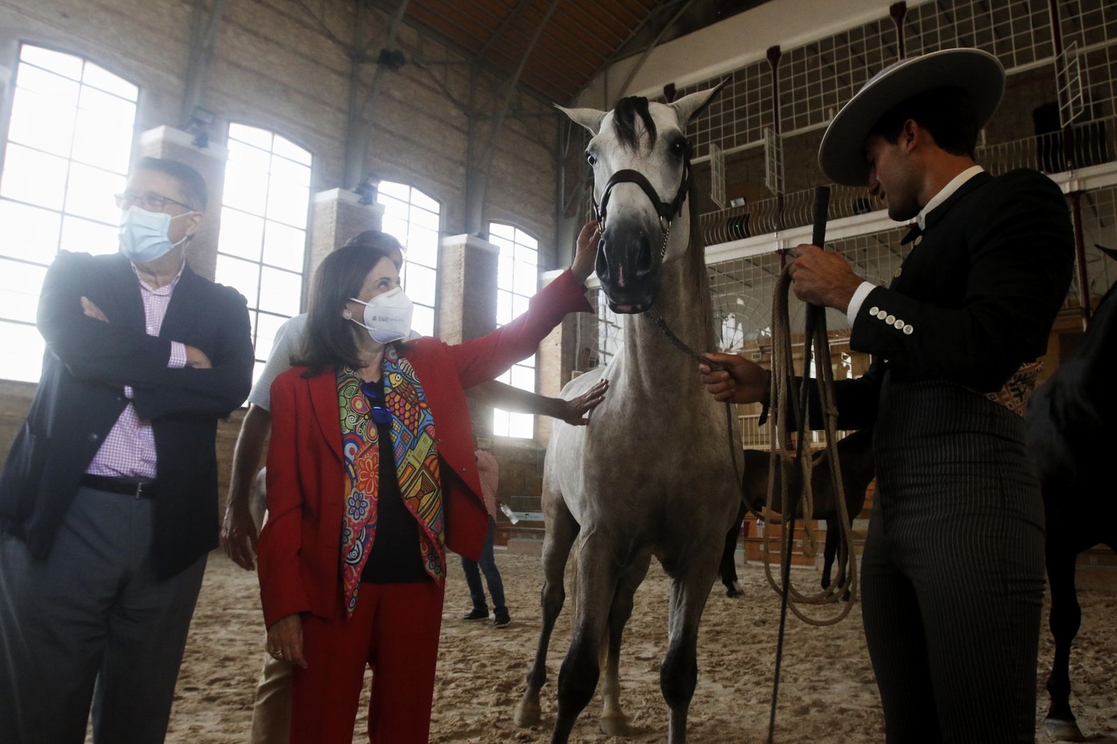 Margarita Robles acaricia a un caballo en su visita a las Caballerizas Reales, que acoge Cabalcor estos días.