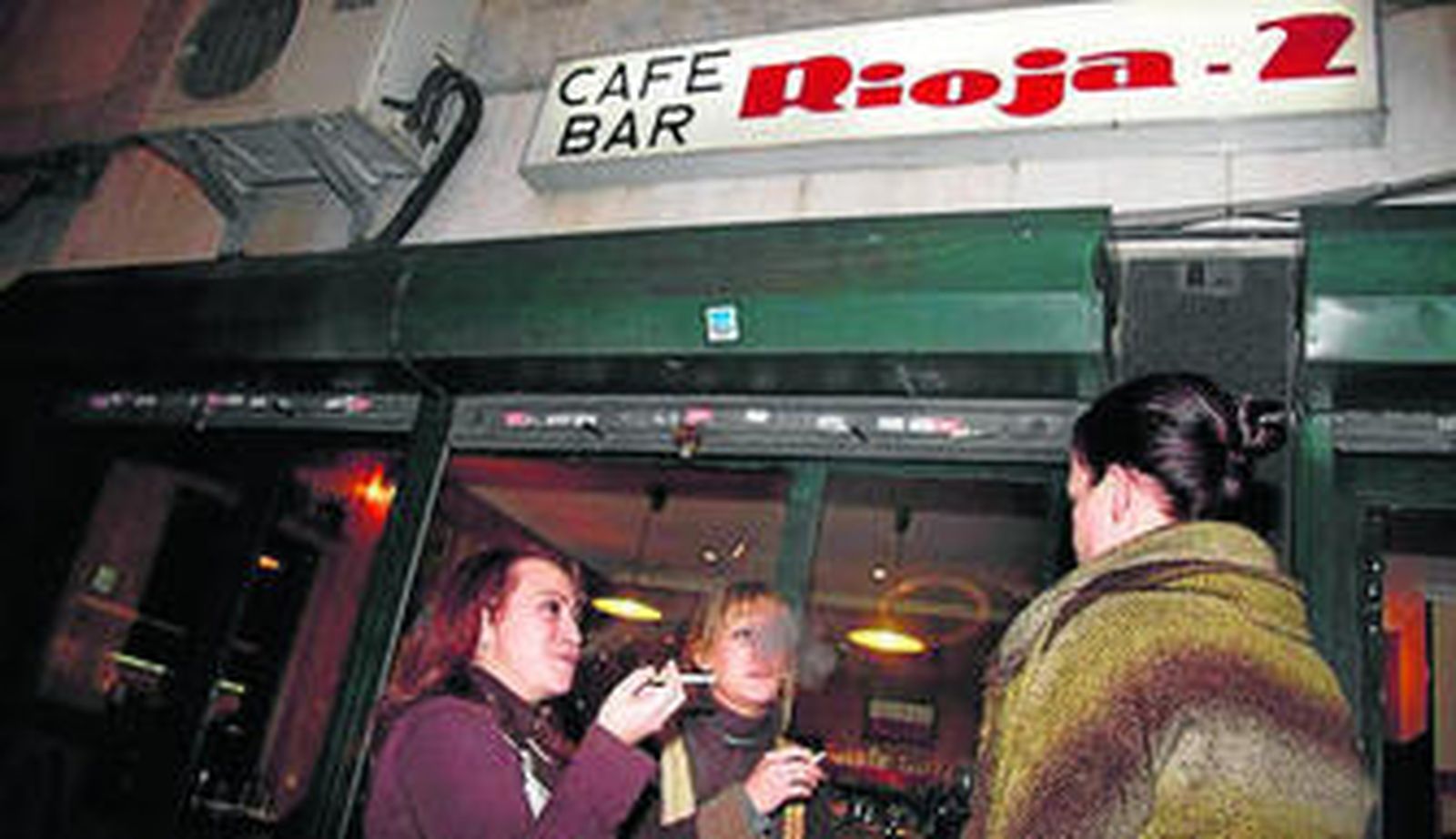 Varias usuarias fumando en la puerta de un bar.