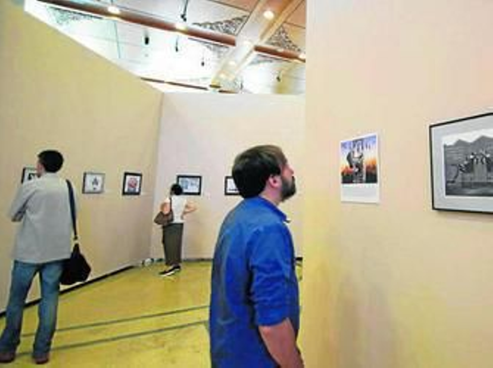 1. Algunos de los visitantes, el día de la inauguración de la exposición, observan las ilustraciones. 2. La crítica política es uno de los temas tratados en las viñetas expuestas.