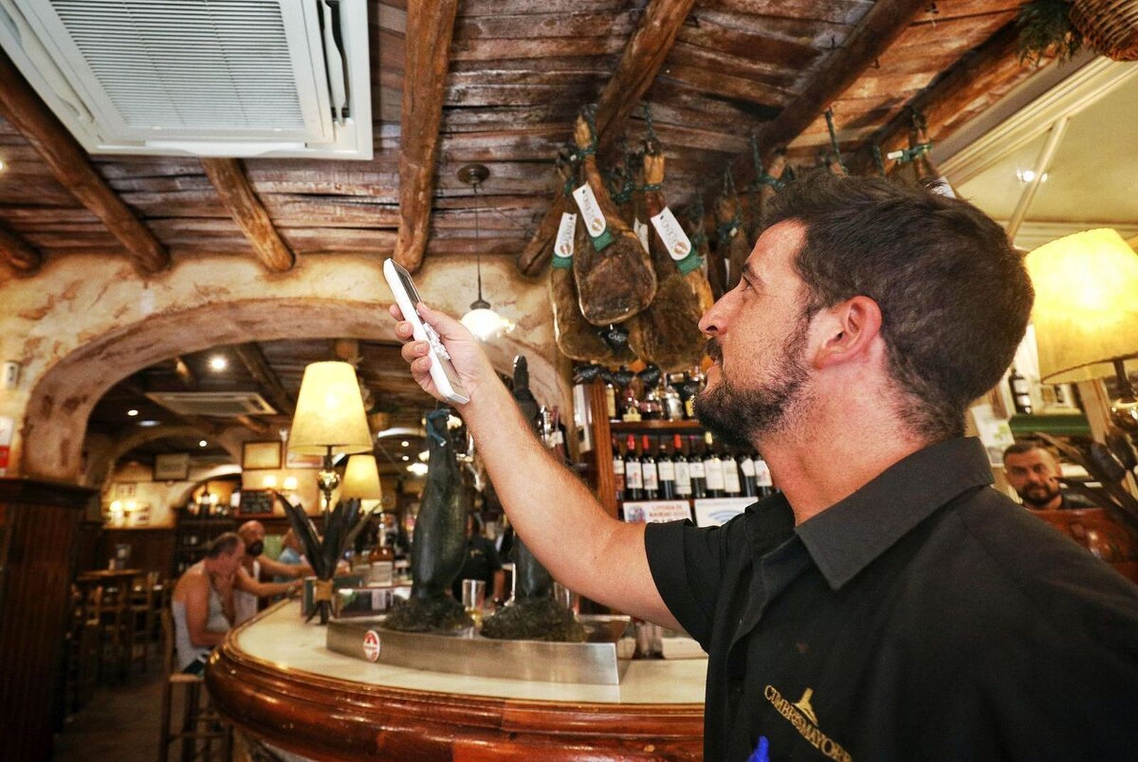 Un camarero, regulando un aparato de aire acondicionado