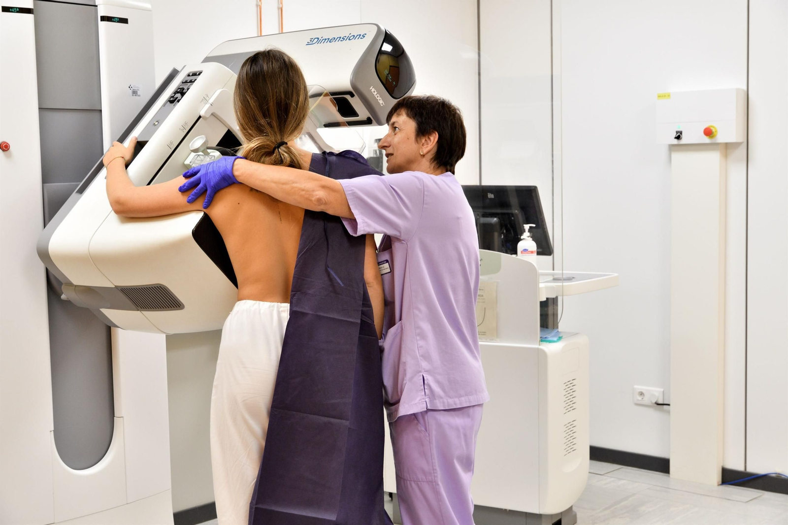Una radióloga ayuda a una paciente para la prueba diagnóstica que detecta precozcmente el cáncer de mama.