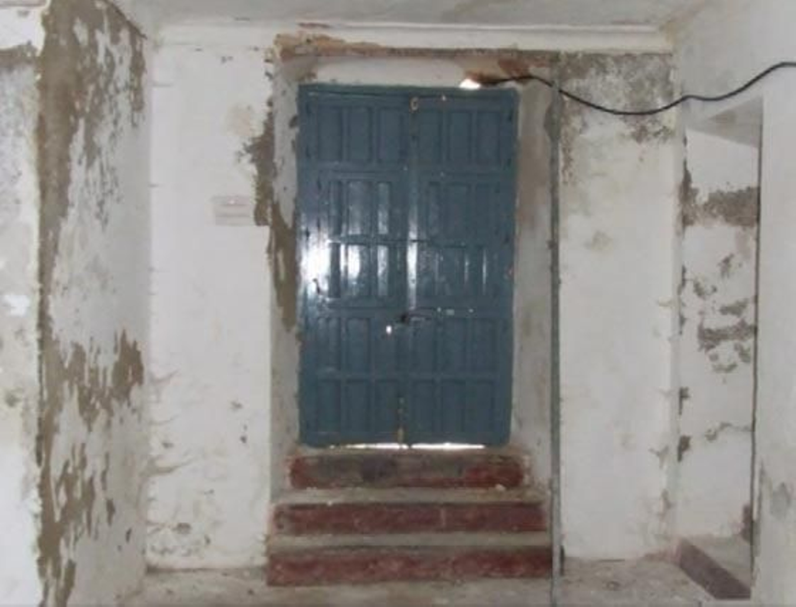 Una puerta del palacio, con las paredes y los escalones deteriorados.