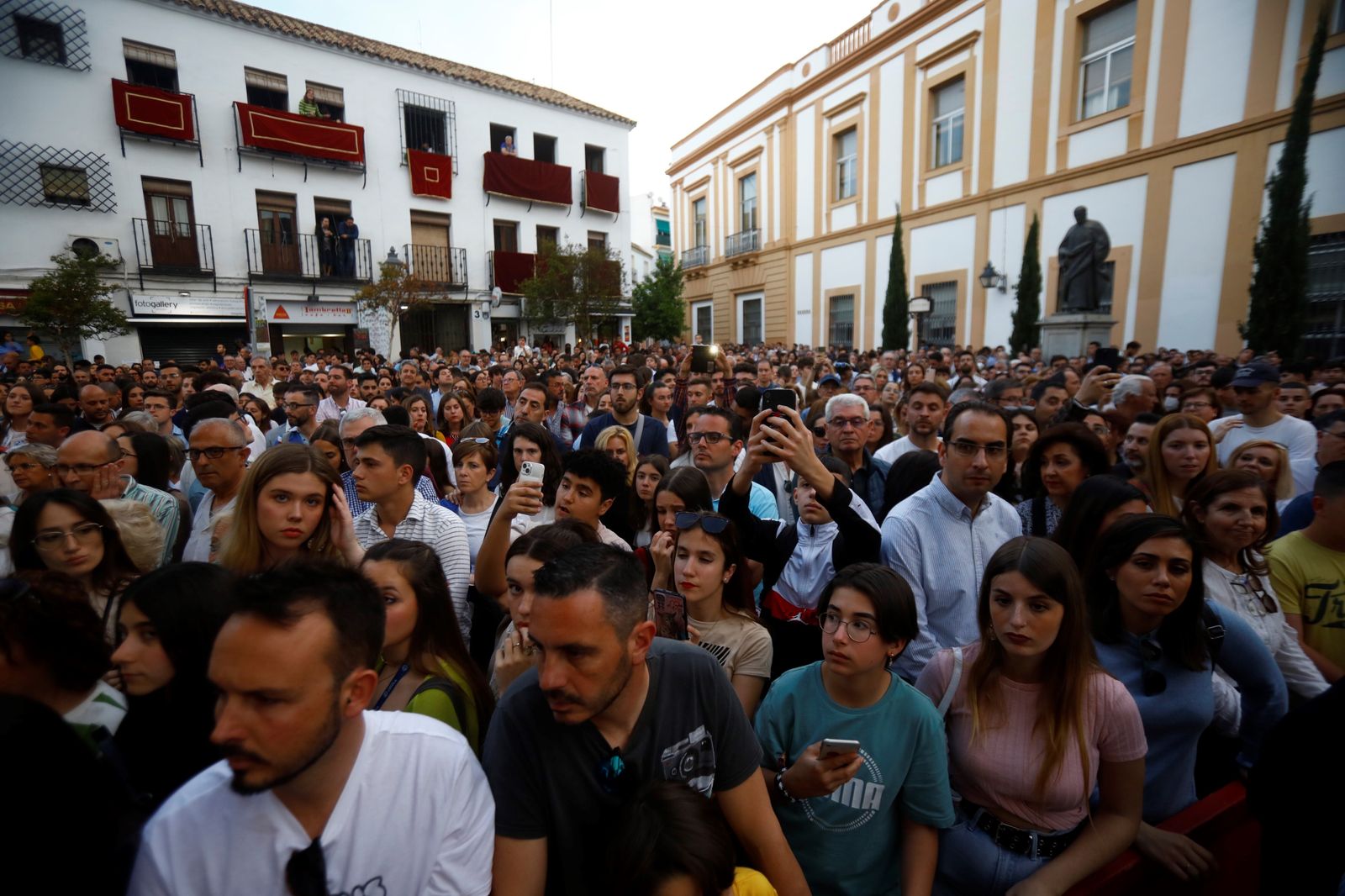 Una multitud de gente espera la salida de una procesión.