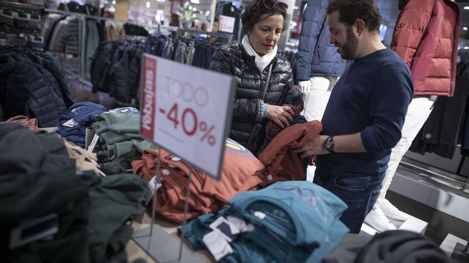 Una pareja busca una prenda en un expositor