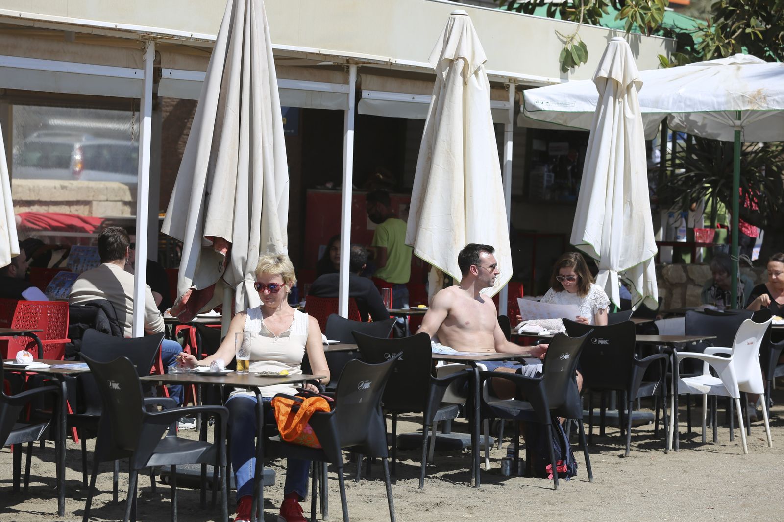Varias personas disfrutan tomando el sol en un chiringuito en Málaga capital.