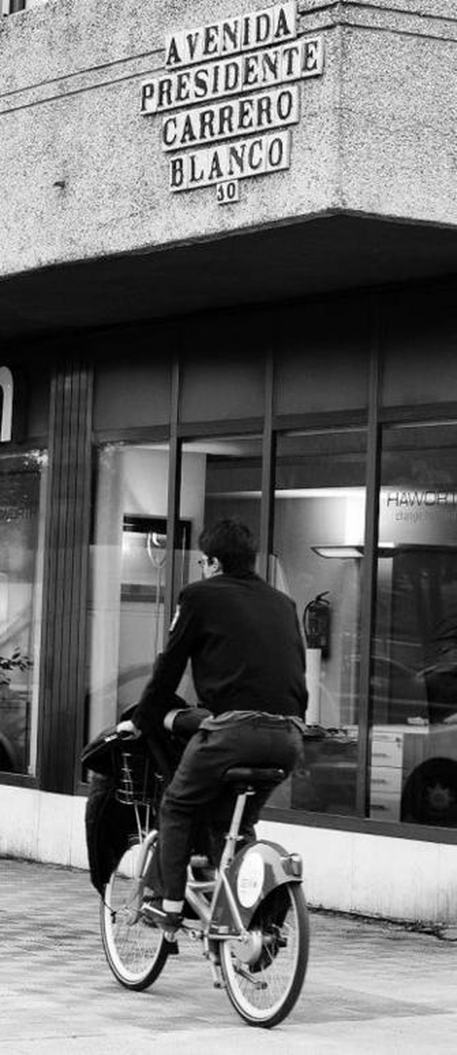 Un joven circula en bici bajo el rótulo de una de las calles afectadas.