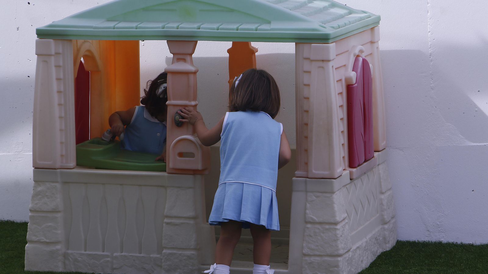 Dos niñas disfrutan de una casa de plástica instalada en el patio de la escuela infantil Chicle.