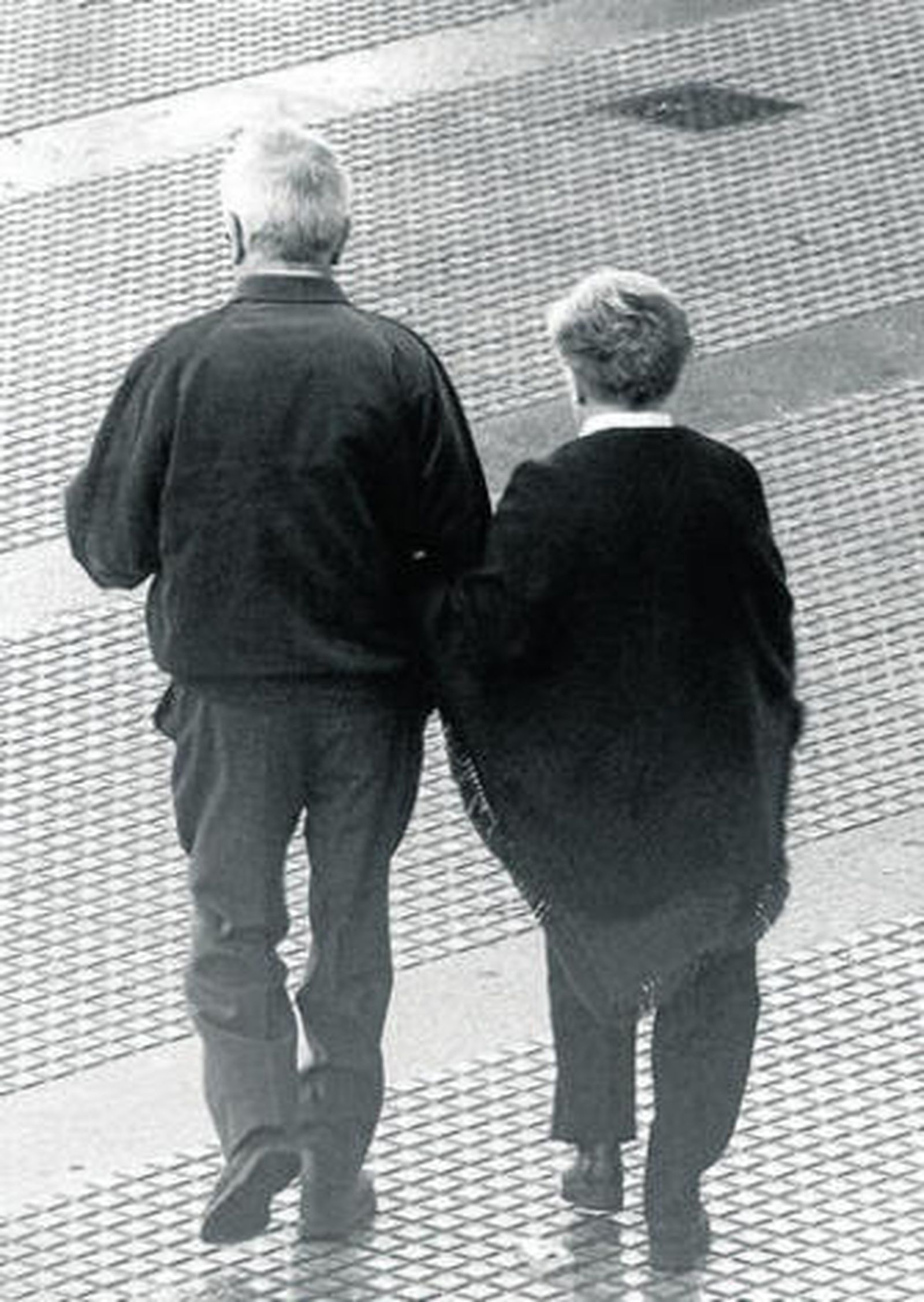 Dos personas mayores pasean por una calle de Cádiz.