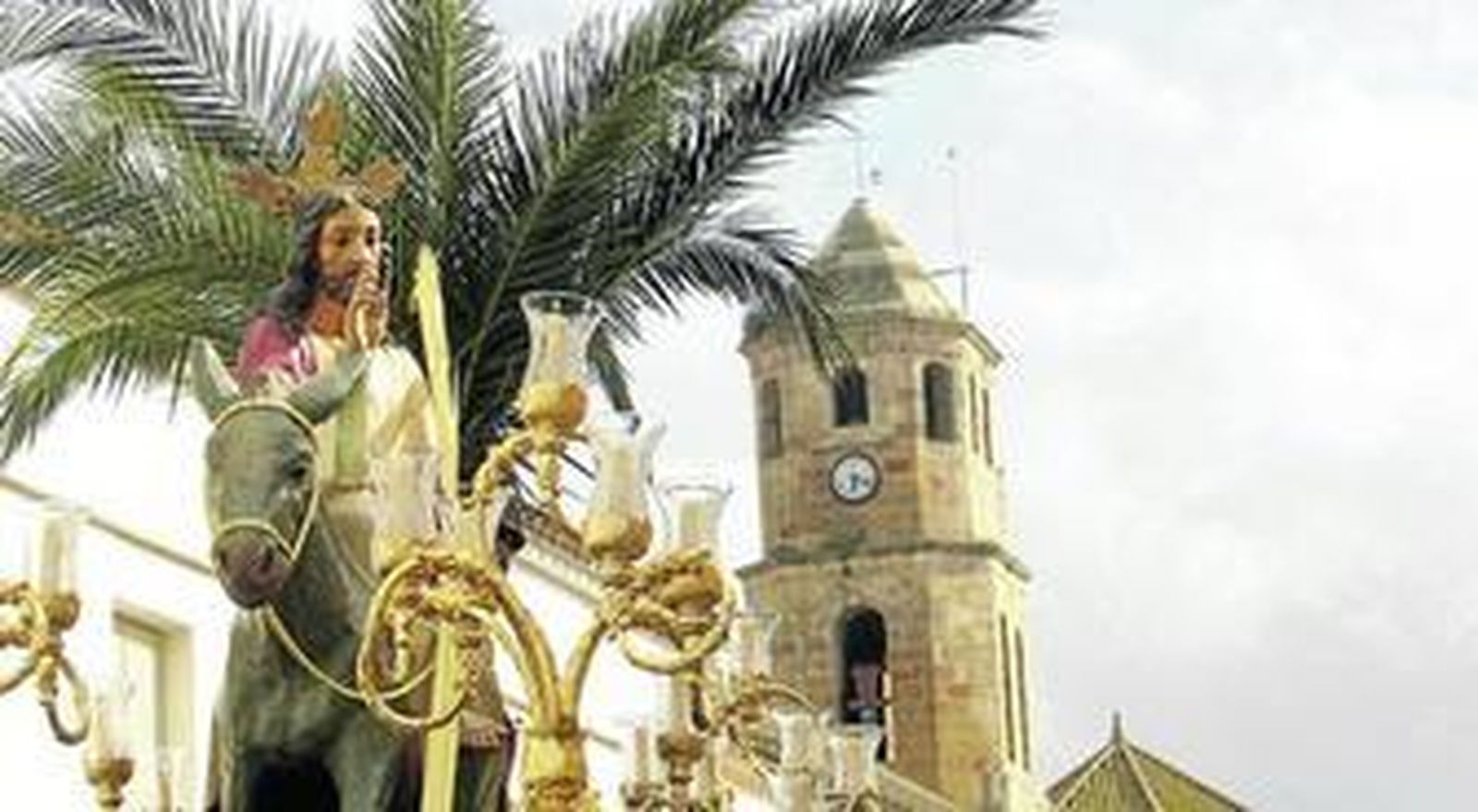La imagen de La Borriquita de Los Barrios avanza por la calle Mayor dejando atrás la torre de San Isidro.