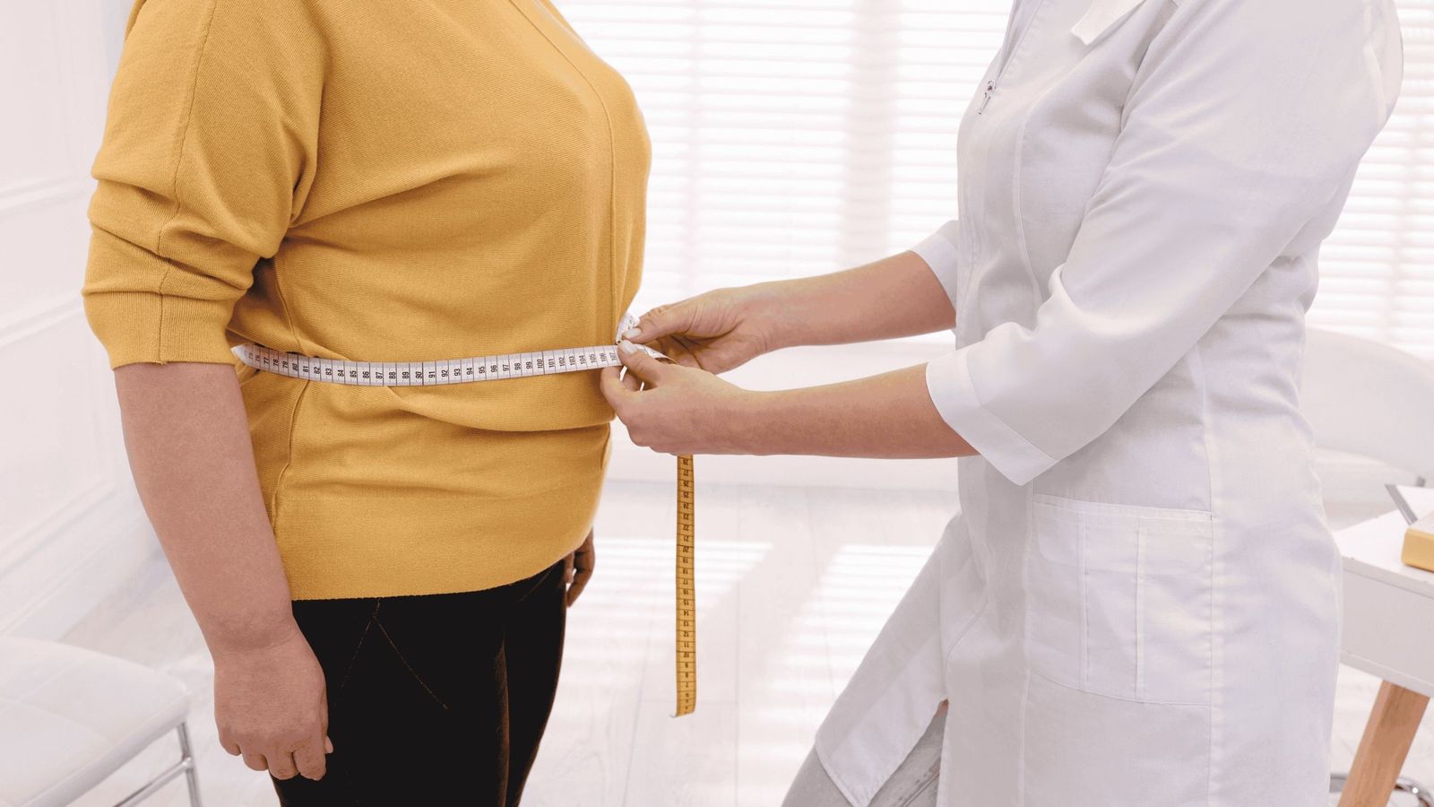 Una médica mide el perímetro abdominal de un paciente.
