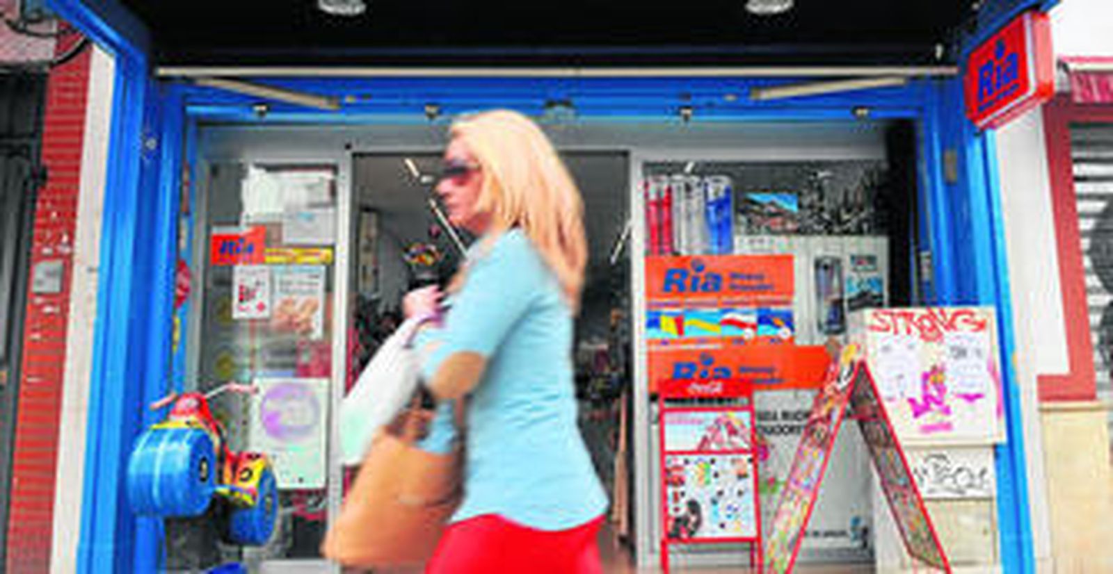 Una mujer pasa por la puerta del establecimiento donde se produjo el atraco.